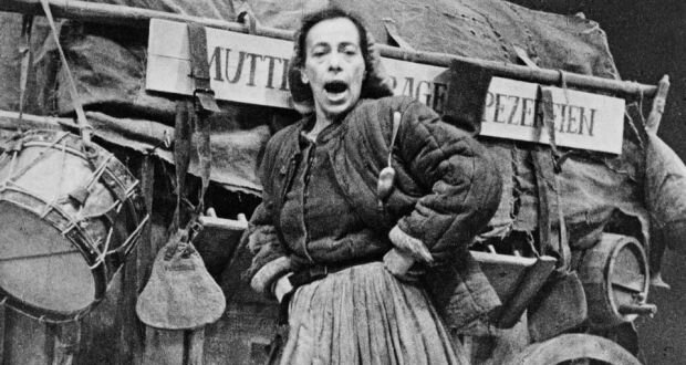 Ilustracja przedstawia kobietę w średnim wieku z ciemnymi włosami zaczesanymi do tyłu, na które założoną ma chustę. Kobieta ubrana jest w ciemna bluzkę, zapinana na guziki, plisowaną spódnicę oraz kufajkę, rodzaj ocieplanego watoliną kaftana, z podwiniętymi rękawami. Za kobietą stoi wóz, na który naciągnięta jest plandeka, która przykrywa zawartość. Na drewnianej konstrukcji wisi długa, prostokątna deska z napisem w języku niemieckim, a wokół zawieszone różne rzeczy: między innymi beczułka, gąsiorek na wodę, bęben etc. Kobieta rękoma podpiera się pod boki, usta ma otwarte, tak jakby śpiewała. 