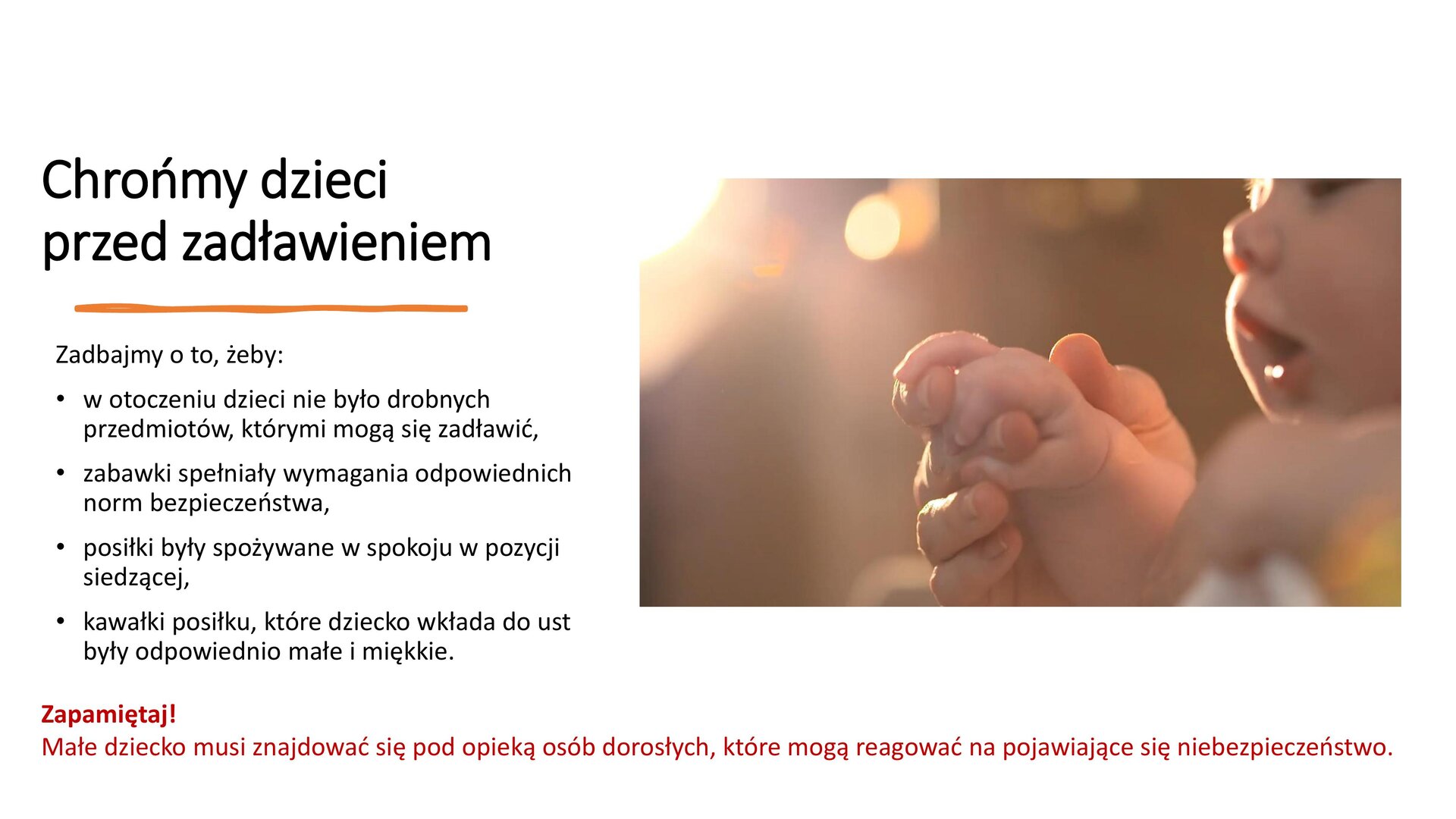 Biały slajd, który przedstawia zdjęcie oraz tekst. W prawym górnym rogu zdjęcie, na którym widoczny jest fragment twarzy małego dziecka oraz jego dłoń, trzymana przez dłoń dorosłego. Z lewej strony slajdu czarny tekst: „Chrońmy dzieci przed zadławieniem. Zadbajmy o to, żeby w otoczeniu dzieci nie było drobnych przedmiotów, którymi mogą się zadławić; zabawki spełniały wymagania odpowiednich norm bezpieczeństwa; posiłki były spożywane w spokoju w pozycji siedzącej; kawałki posiłku, które dziecko wkłada do ust były odpowiednio małe i miękkie”. U dołu slajdu czerwony tekst: „Zapamiętaj! Małe dziecko musi znajdować się pod opieką osób dorosłych, które mogą reagować na pojawiające się niebezpieczeństwo”.