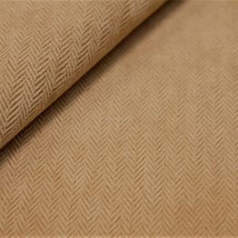 Na zdjęciu pokazano próbkę tkaniny flockowej. Materiał jest w jasnobrązowym kolorze i posiada wyraźną fakturę splotu w tak zwaną jodełkę.