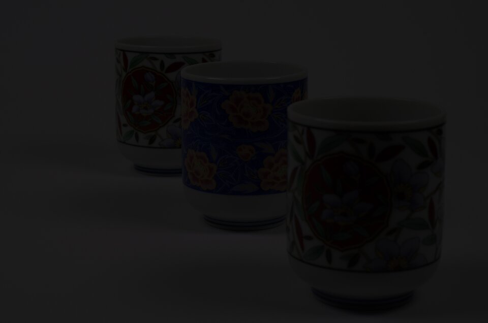 Niedoświetlona fotografia kubków ustawionych w perspektywie zbieżnej. Obraz jest prawie całkowicie czarny. 