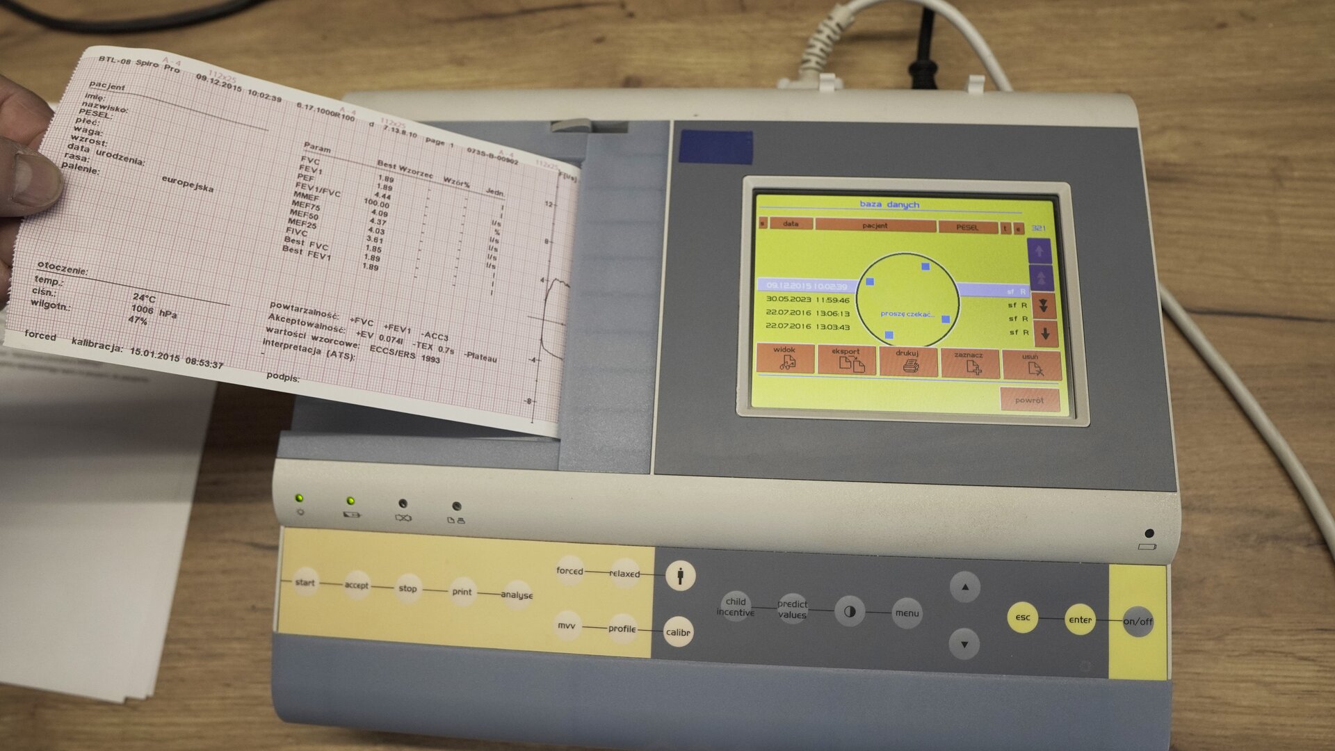Na zdjęciu pokazany jest spirometr oraz wydruk danych znajdujących się na jego ekranie. 