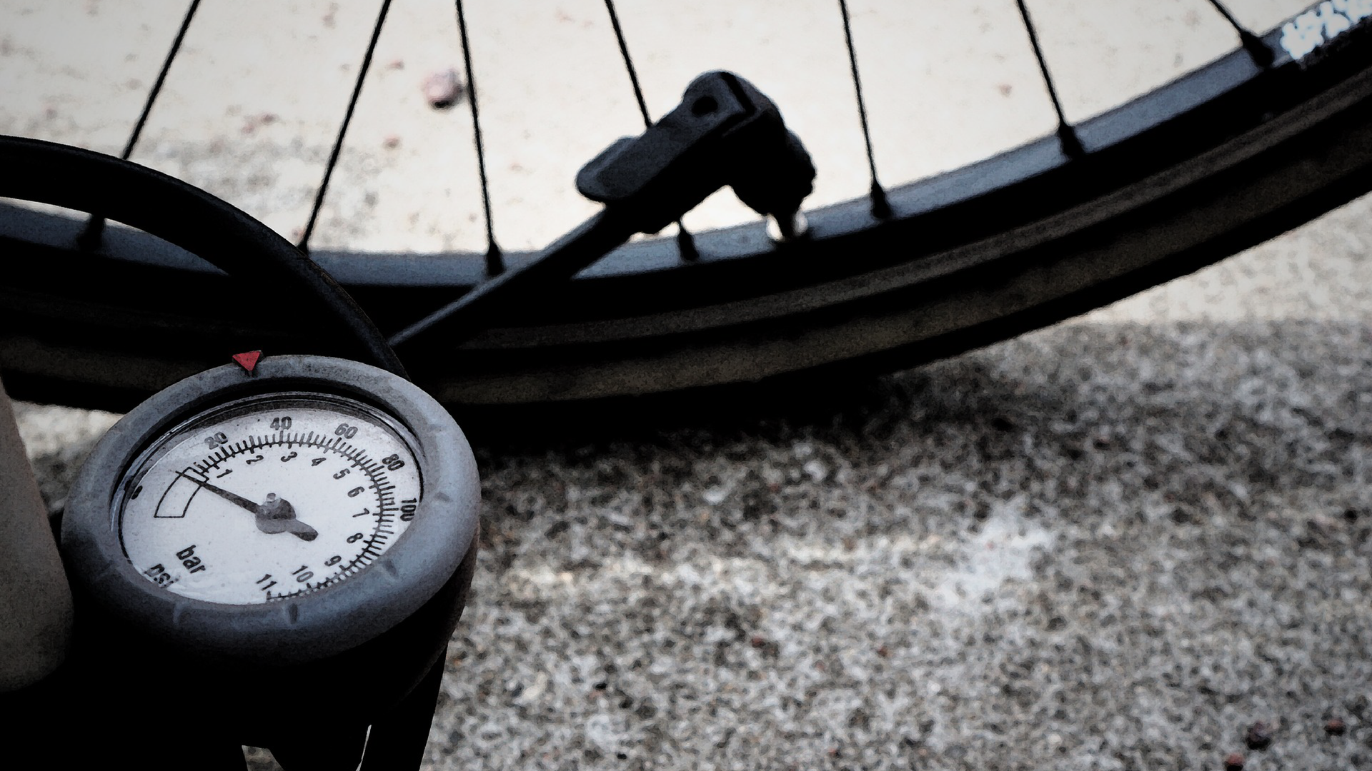 Zdjęcie przedstawia pompkę. Końcówka pompki założona jest na wentyl opony. Widoczny jest manometr pompki.