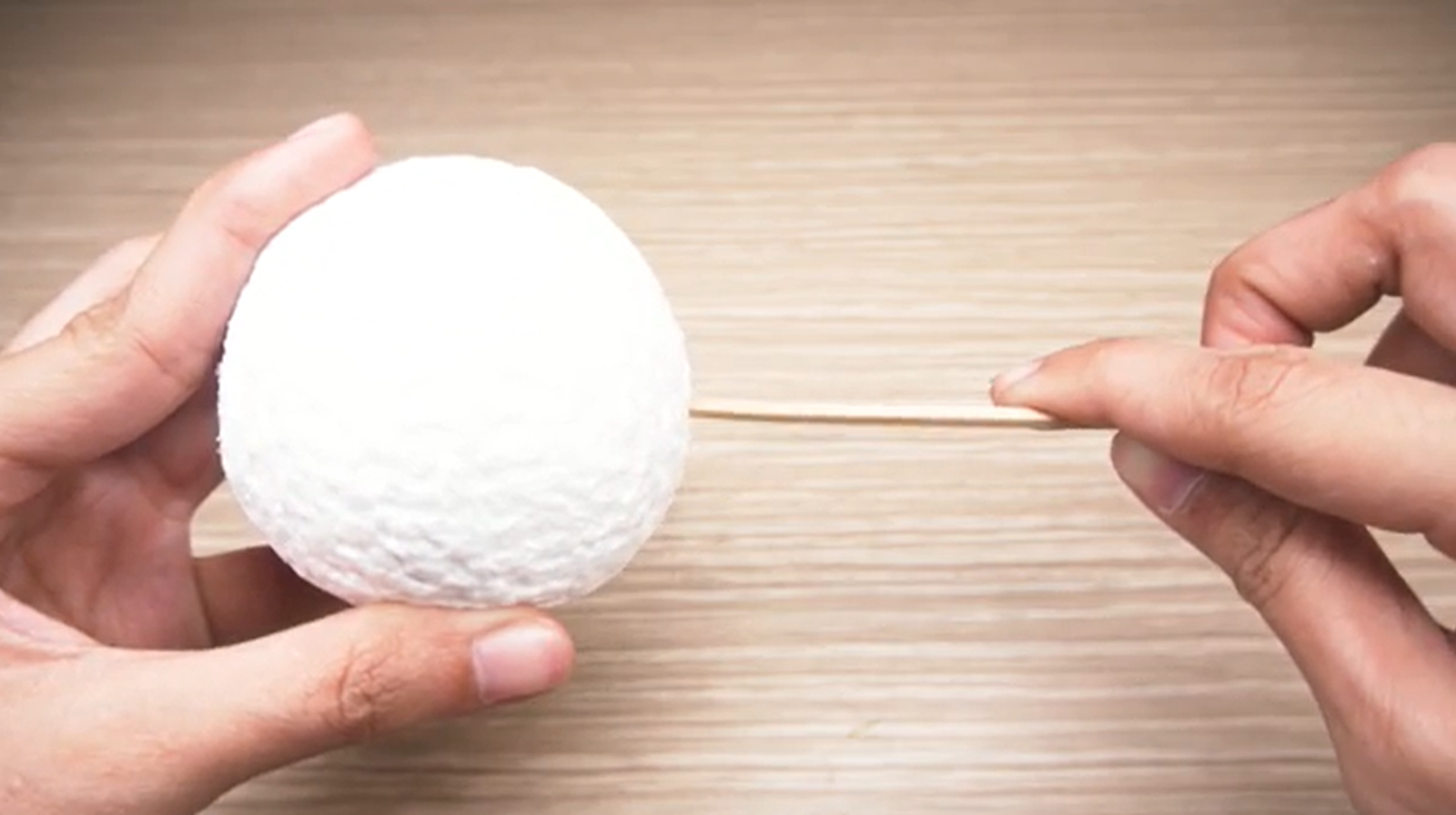 Zdjęcie przedstawia styropianową kulę przebitą drewnianym patykiem.