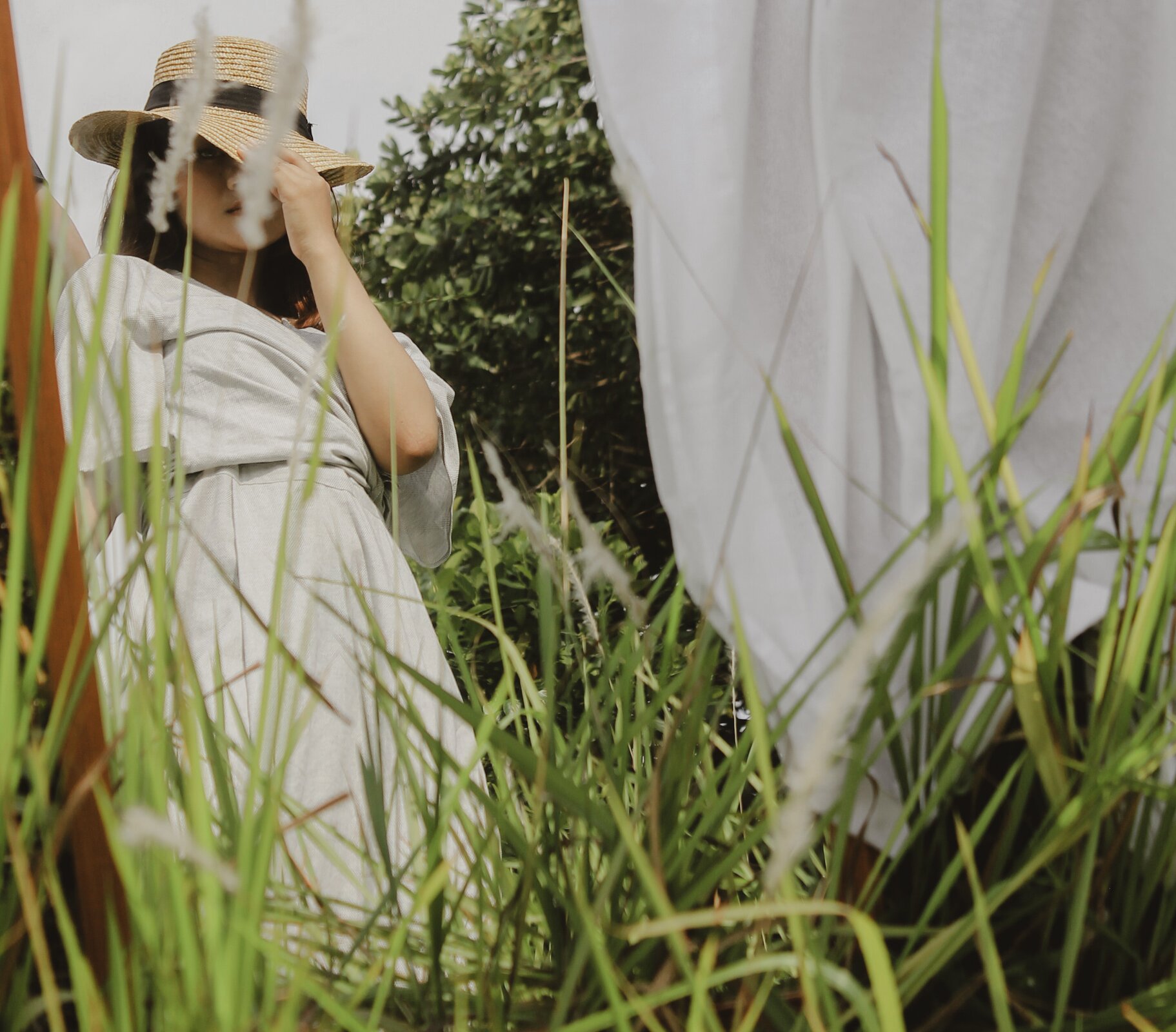 Ilustracja przedstawia kobietę w białej sukience i słomkowym kapeluszu 