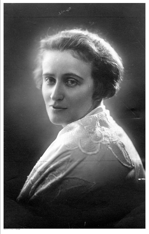 Fotografia portretowa młodej kobiety. Kobieta ma krótkie włosy i lekko się uśmiecha. Patrzy wprost na osobę wykonującą zdjęcie.