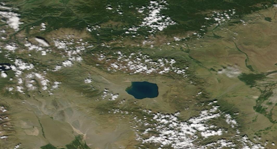 Zdjęcie satelitarne, w centrum którego jest okrągły zbiornik wodny. Na północ od jeziora są tereny zielone, a wokół zbiornika jasnobrązowe i brązowe, gdzieniegdzie zielone.    