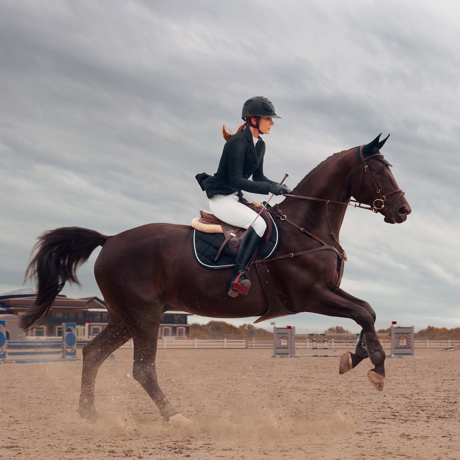 Zdjęcie przedstawia kobietę w stroju jeździeckim, ujeżdżającą brązowego konia. 
