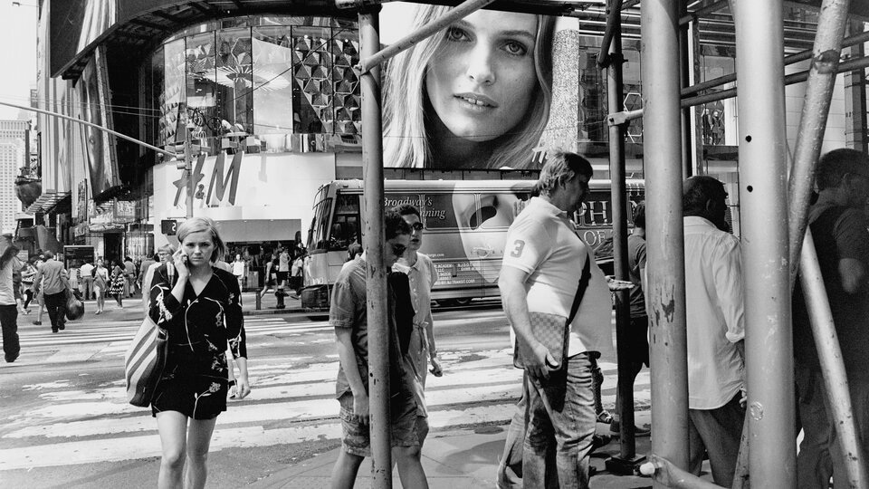 Ilustracja przedstawia fotografię Lee Friedlandera pt. „Walk the Line”, na której ukazana została przestrzeń miejskiej metropolii. Na pierwszym planie widać licznych przechodniów, rusztowania, w tle przejeżdżający autobus i banery reklamowe na budynkach. Jeden z nich przedstawia twarz kobiety.