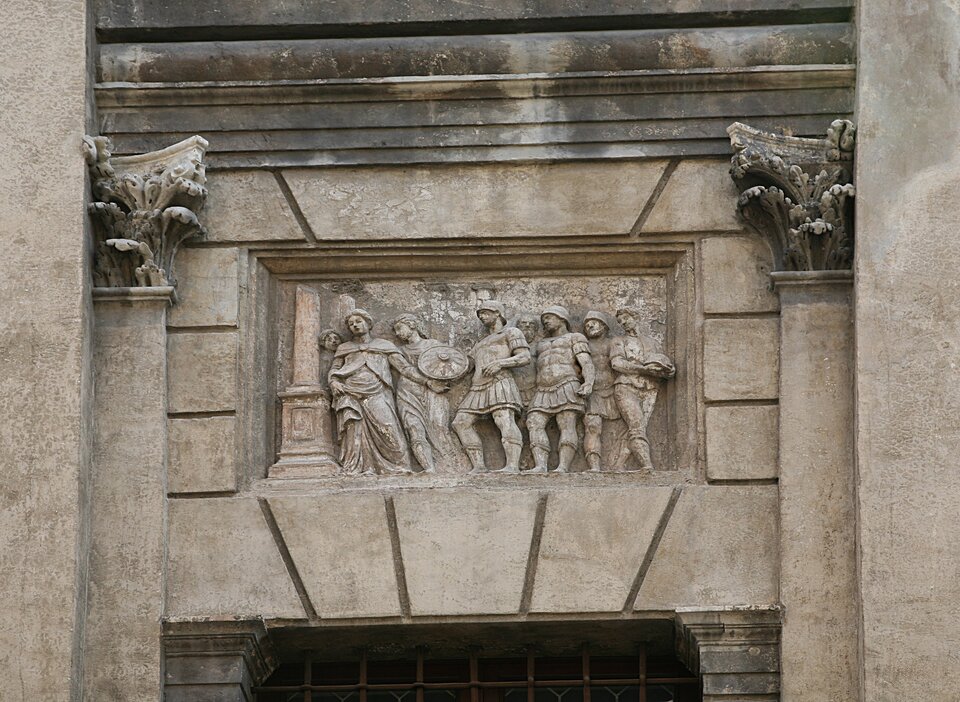 Ilustracja o kształcie poziomego prostokąta przedstawia  detal z dekoracji fasady nad Palazzo Valmarana. Płaskorzeźba nad oknem ukazuje siedem osób – kilka z nich w antykizujących zbrojach rzymskich. Po bokach znajdują się pilastry z korynckimi głowicami. 