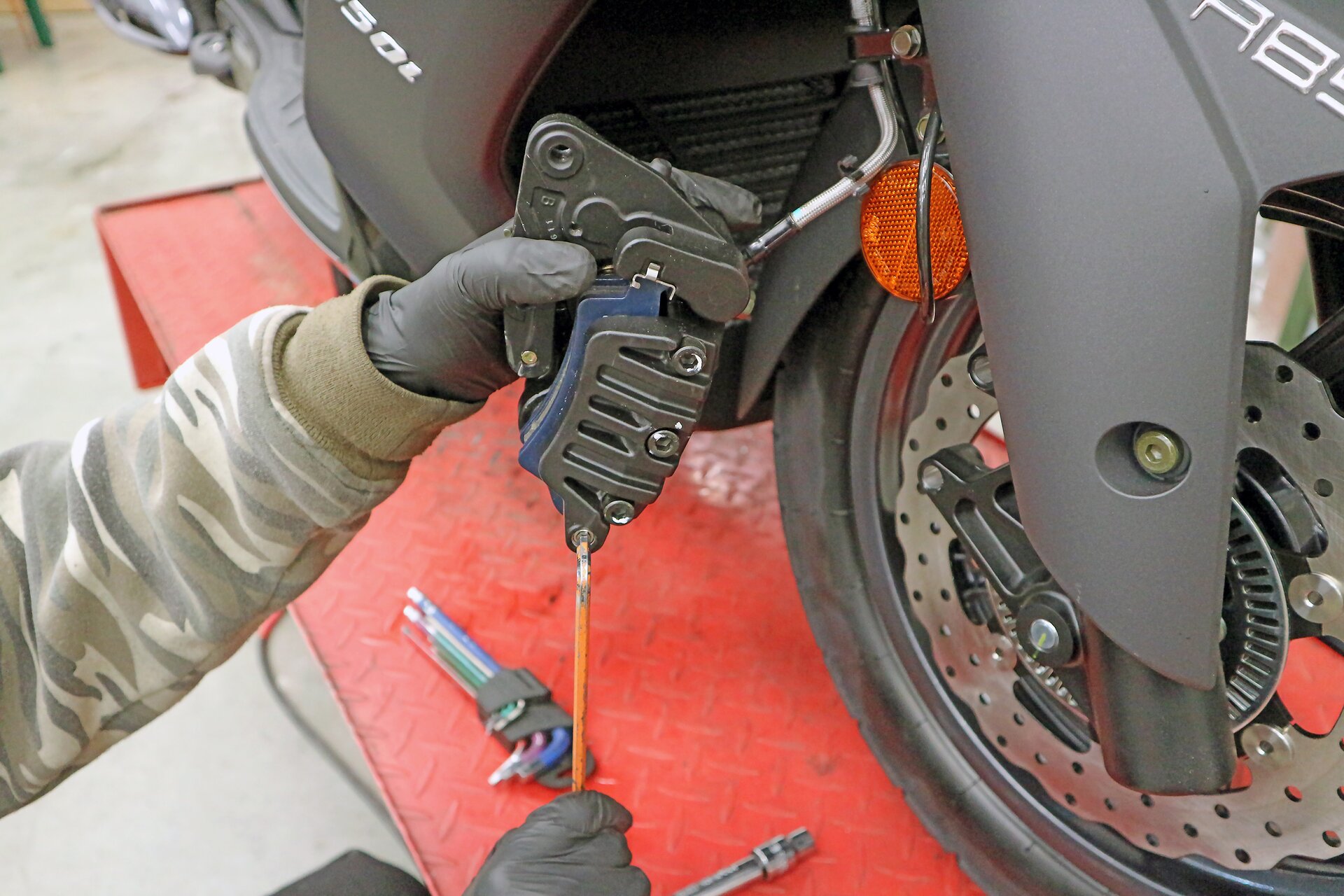 Na ekranie przedstawiono wykręcanie sworznia mocującego klocki hamulcowe w zacisku niesymetrycznym.