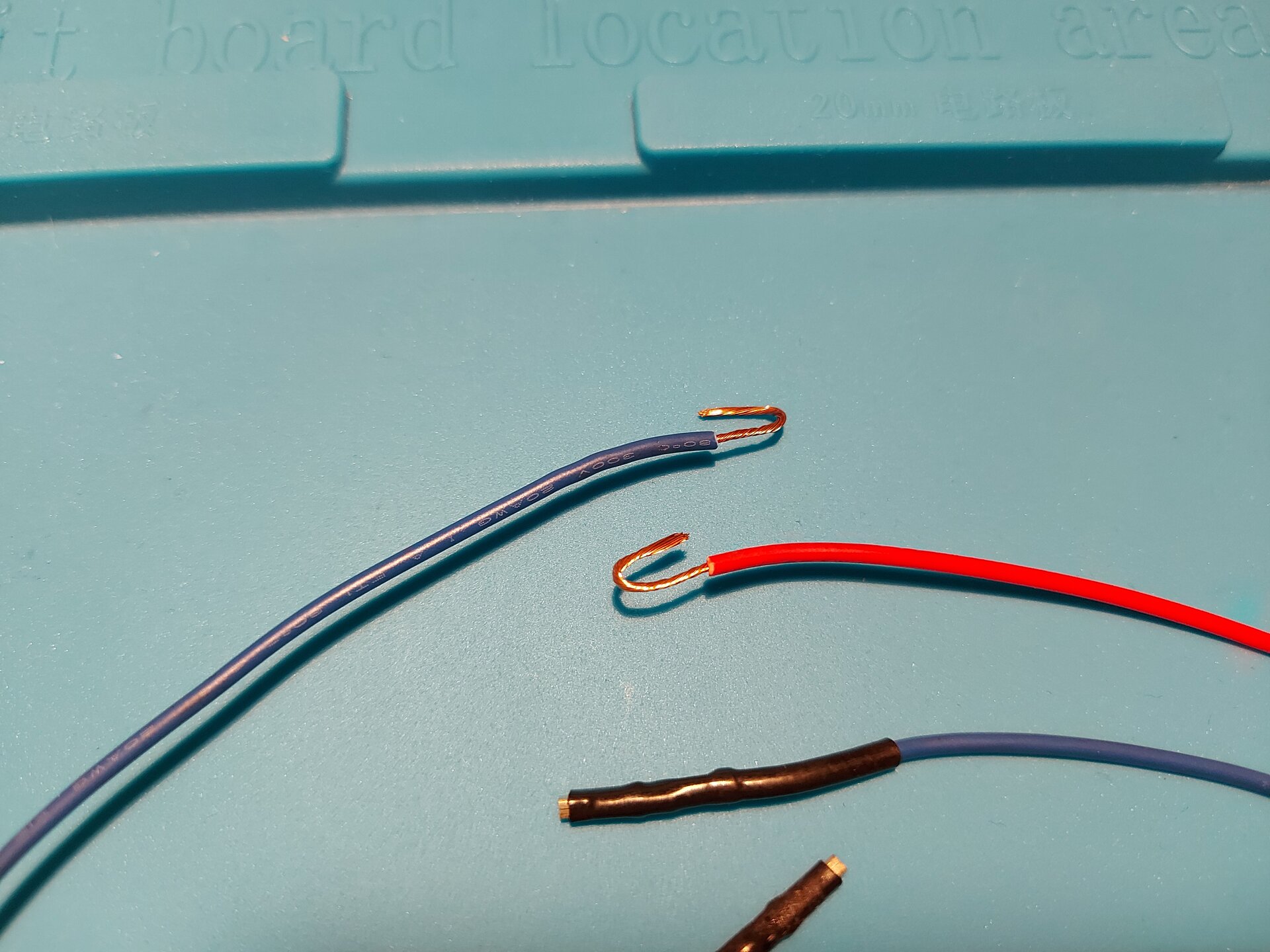 Zdjęcie przedstawia 2 przewody z usuniętą izolacją tym samym odsłaniając miedziane wnętrze, które wygięto w małe haczyki.