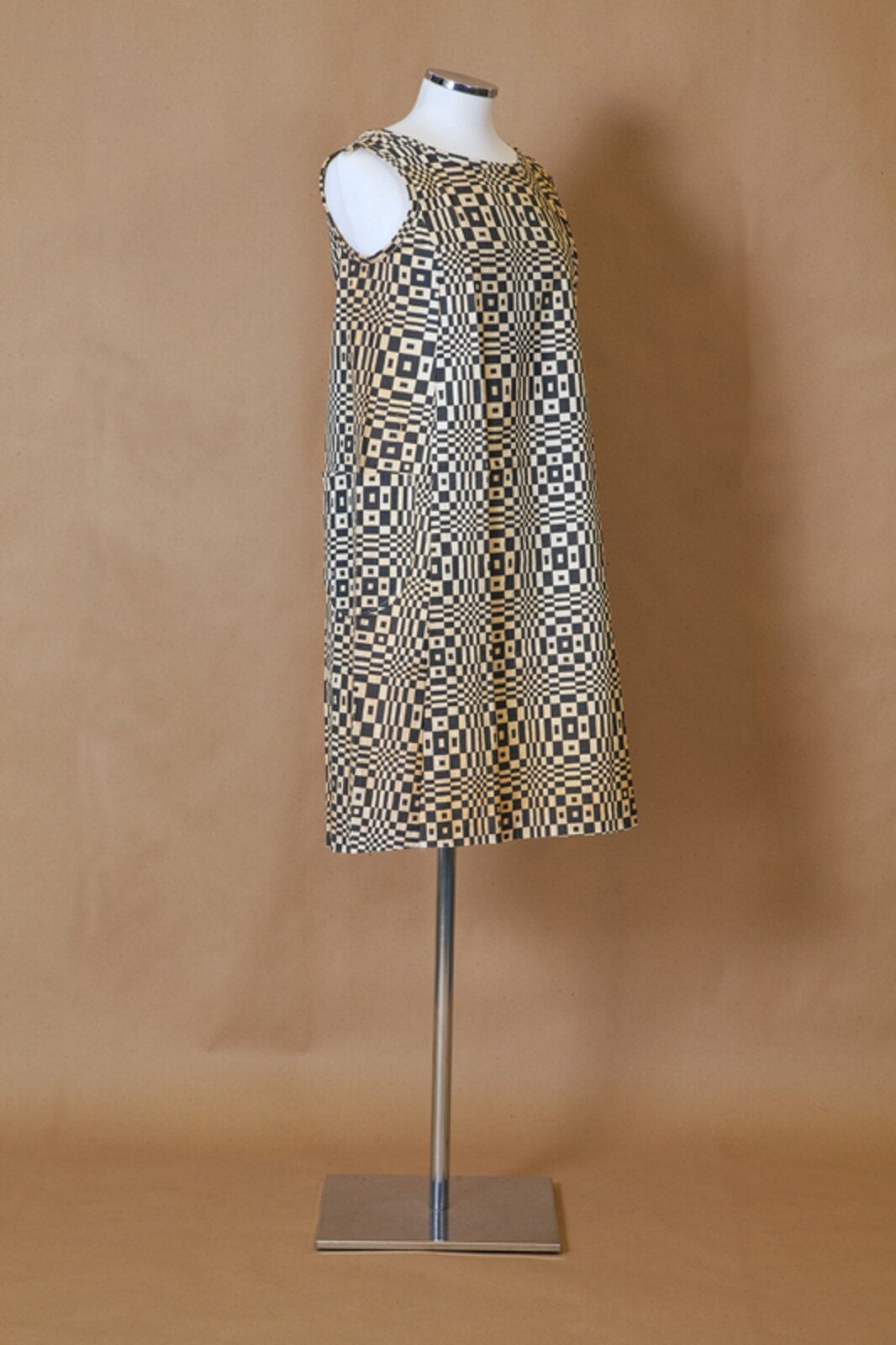 Ilustracja przedstawia sukienkę na manekinie. Sukienka jest przykładem wykorzystania wzorów op‑artu w sztuce użytkowej. Umieszczone są na niej biało czarne wzory.