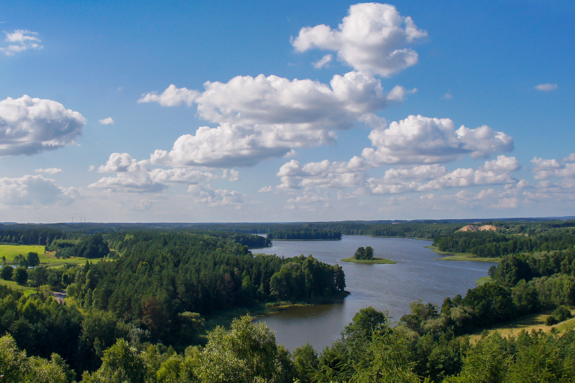 Fotografia ukazuje jeziora Pojezierza Mazurskiego otoczone drzewami liściastymi.