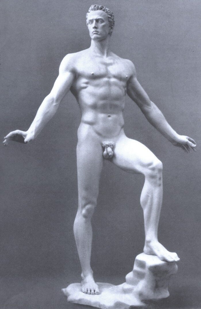 Fotografia przedstawia posąg nagiego młodego mężczyzny z rozłożonymi na bok rękami, który dumnie pręży swoje ciało.