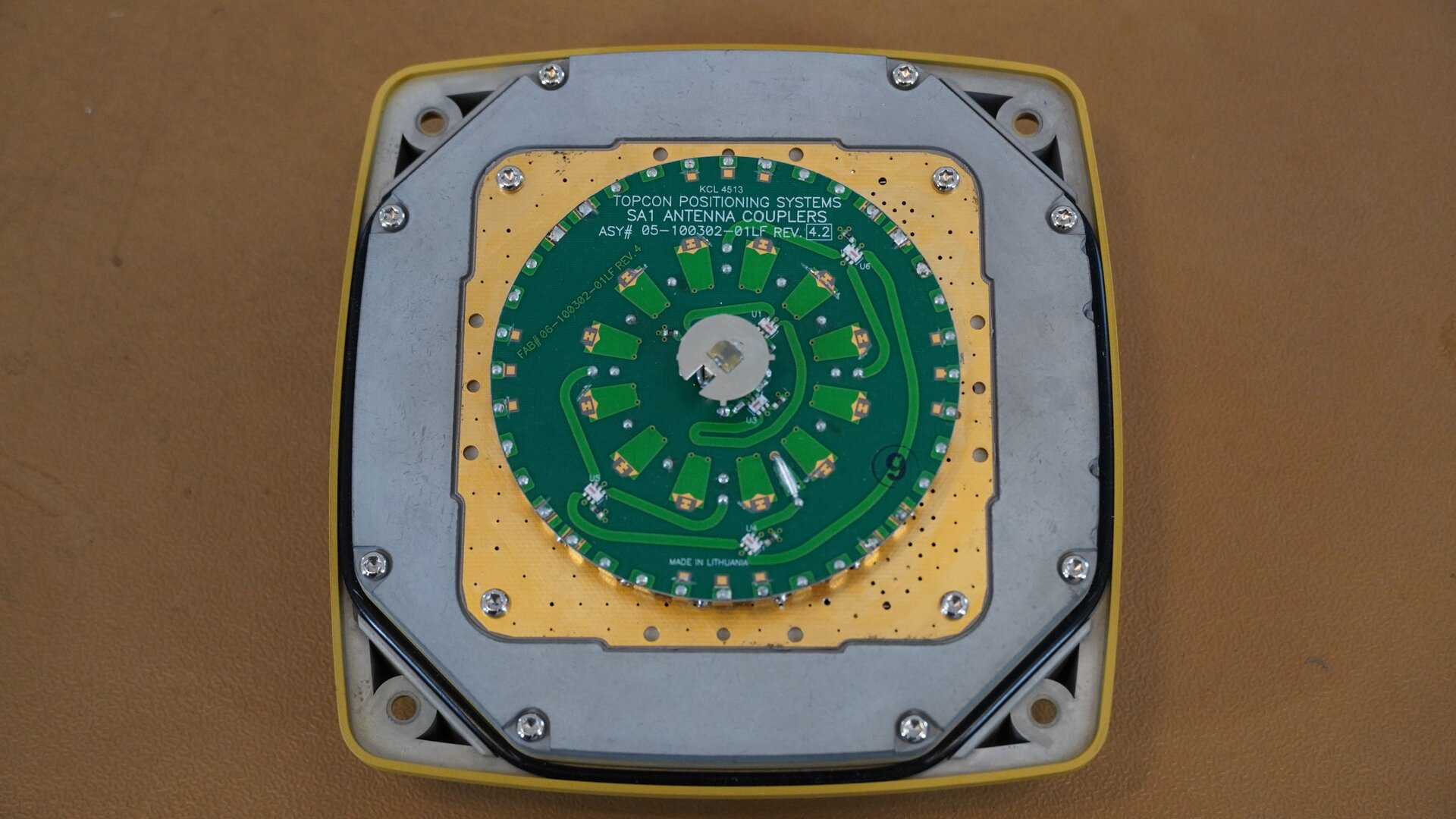 Na zdjęciu przedstawiono zbliżenie wnętrza odbiornika GNSS widocznego po zdjęciu obudowy. W środku znajduje się okrągła, zielona płytka z układem scalonym będąca elementem anteny GBS służącej do odbioru sygnału z satelity, zaś znajdujący się w centralnej części metalowy pierścień to antena bluetooth.