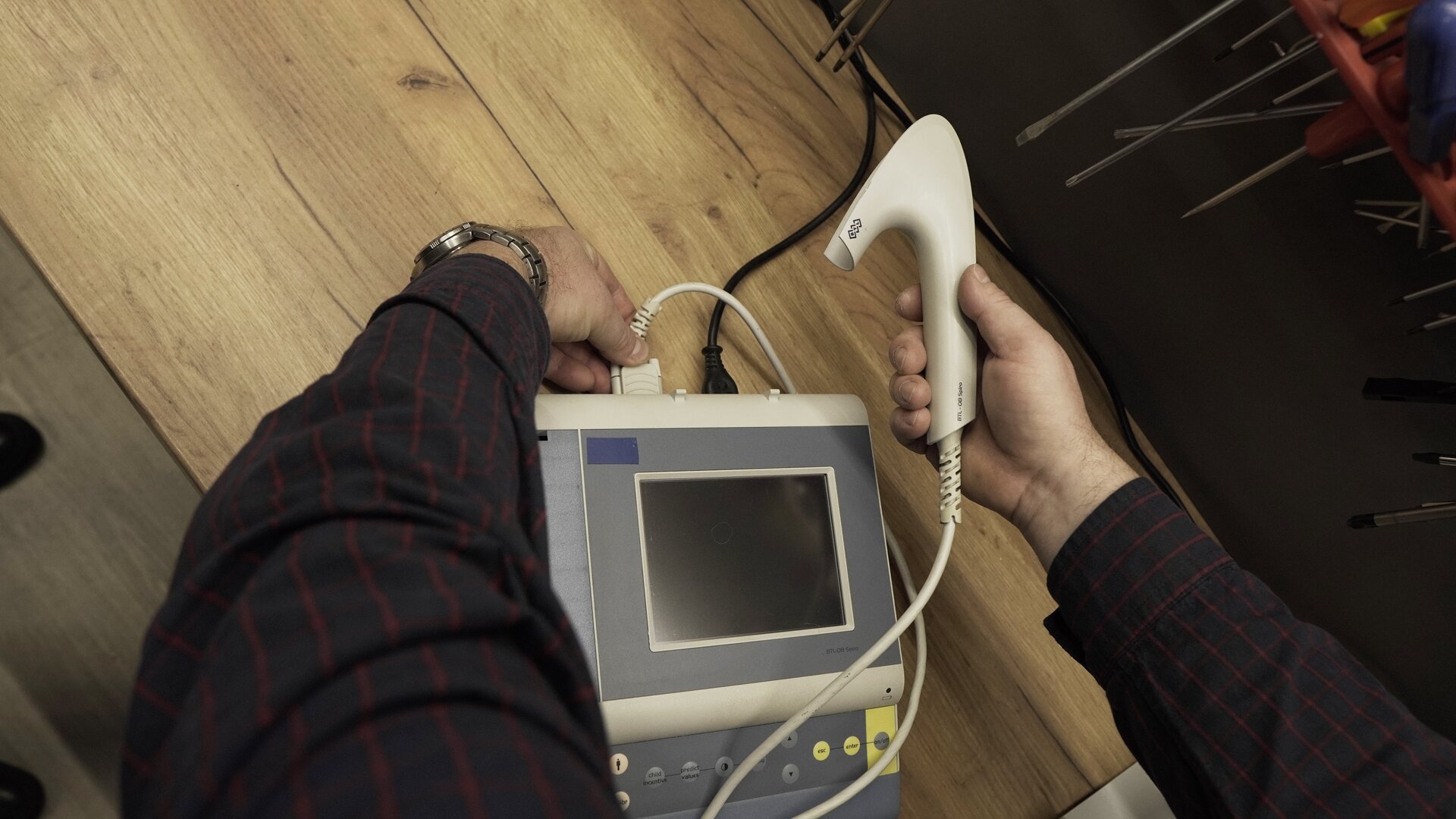 Na zdjęciu technik dokręca wtyczkę RS232 do gniazda spirometru. 