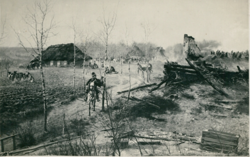 Ilustracja przedstawia fragment wioski. Wzdłuż drogi zasadzone młode brzozy. Niektóre domy się ostały, reszta spalona. 