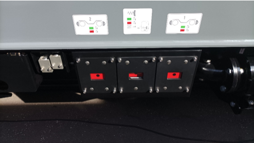 Ilustracja przedstawia zdjęcie boku pudła wagonu ze zbliżeniem na wskaźniki hamowania. Przedstawione są za pomocą trzech okienek, każde z tych okienek pokazuje symbol – czerwone tło z czarną kropką w środku.