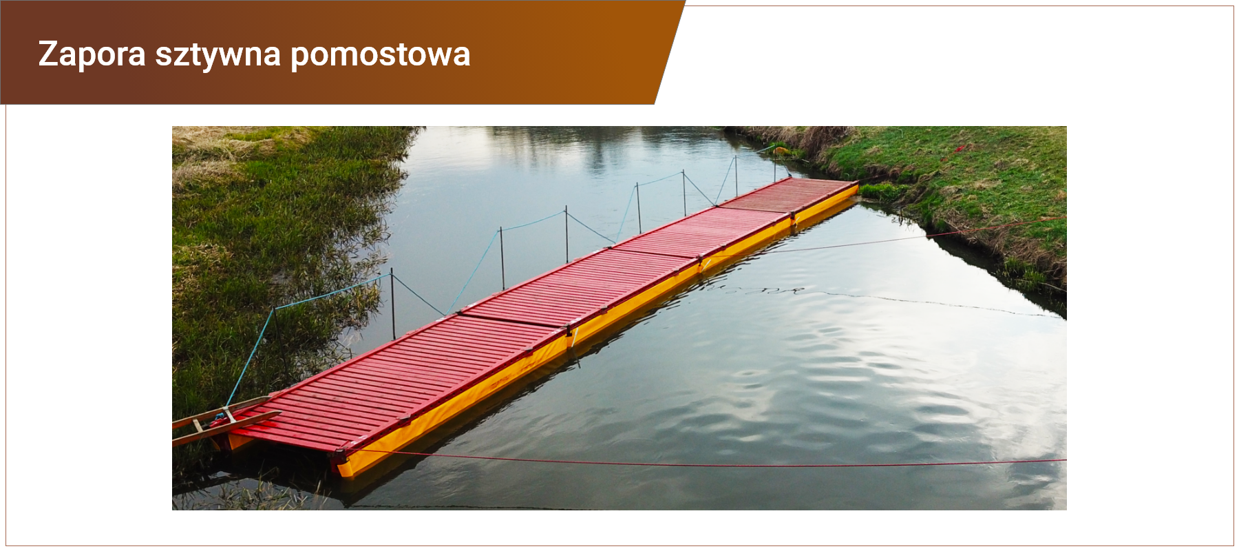 Zdjęcie w ramce z podpisem: zapora sztywna pomostowa. Zdjęcie przedstawia czerwony pomost ustawiony skośnie w poprzek rzeki. Po bokach pomostu jest pomarańczowe tworzywo stanowiące zaporę. Pomost z jednej strony posiada poręcz ze słupków i liny. Z drugiej strony przytwierdzony jest linami do brzegu. Do pomostu od jednego z brzegów prowadzi drabina. Przy brzegach rzeki zielona roślinność. 