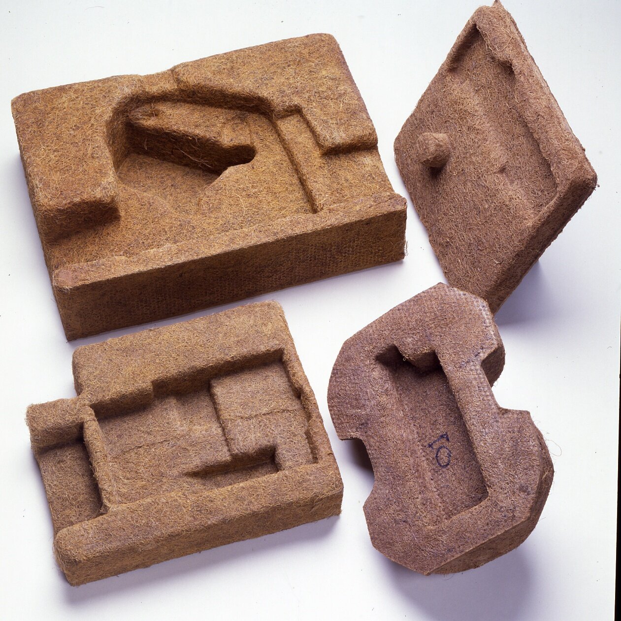 Na zdjęciu widoczne cztery prostokątne bryły z włókna kokosowego. Środek każdej z nich jest uformowany w inny, wklęsły kształt.