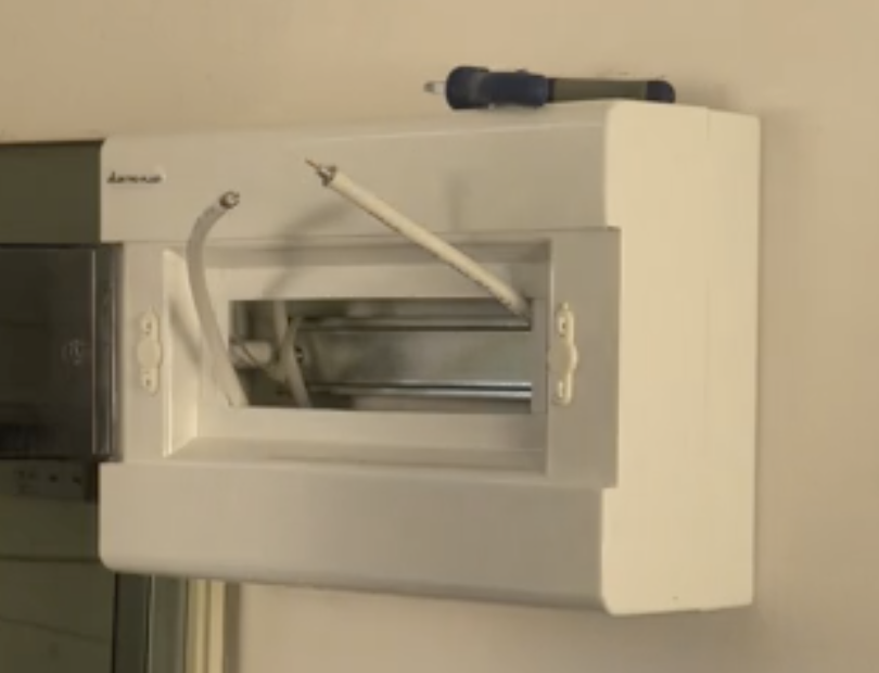 Zdjęcie przedstawia skrzynkę. Obudowa ma kształt prostopadłościanu. Na środku widoczny jest otwór, wewnątrz znajdują się kable.