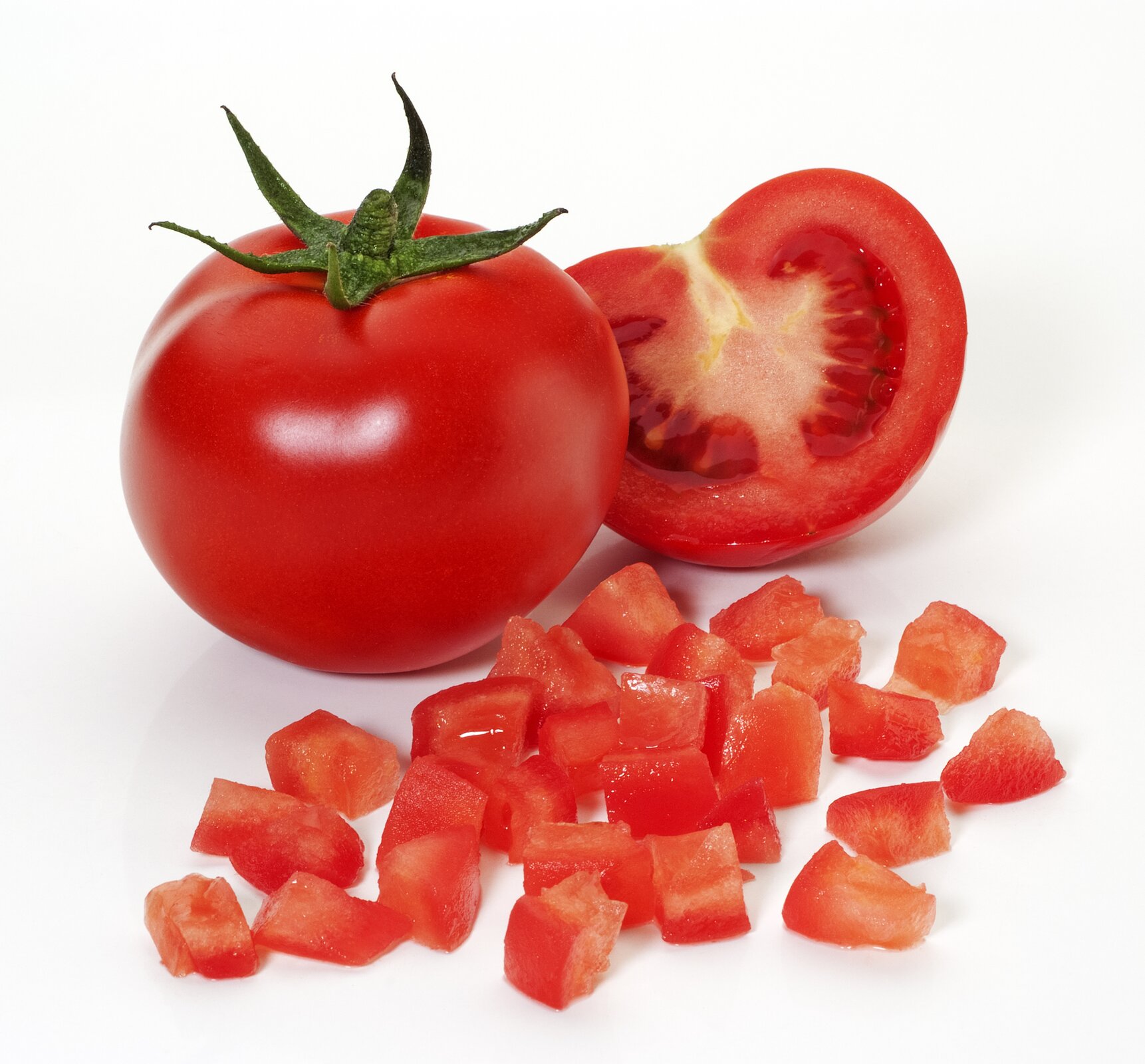 Zdjęcie przedstawia pomidora pokrojonego techniką concasse. Na białym tle widoczne są na pierwszym planie kostki pomidora, a za nimi cały pomidor i połówka pomidora.