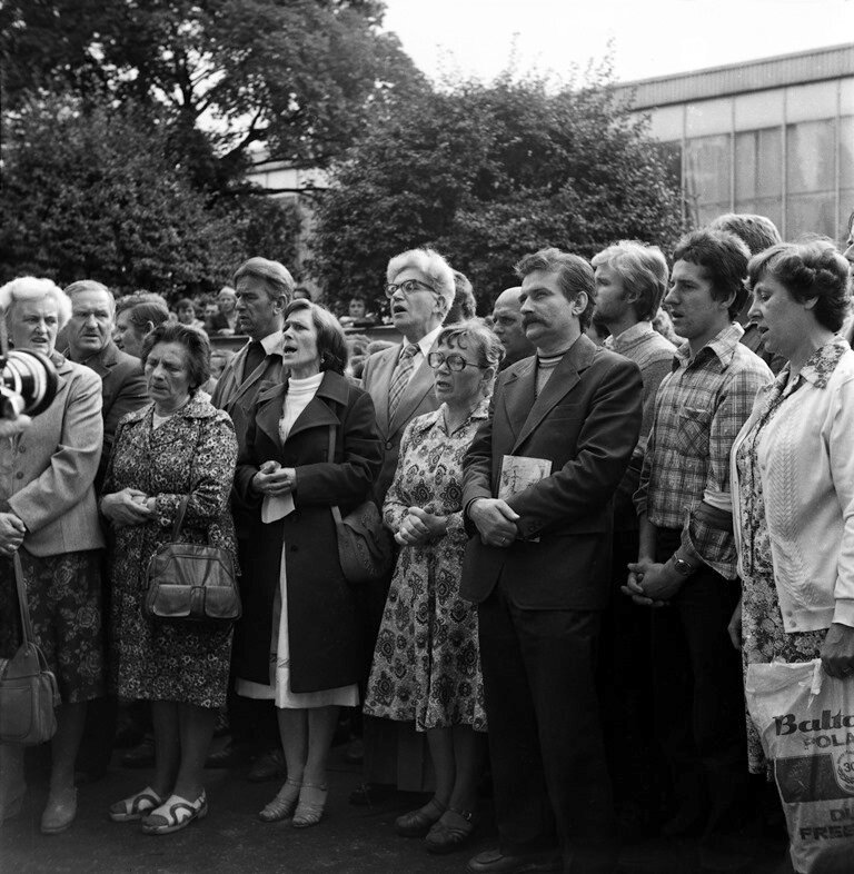na zdjęciu grupa ludzi podczas mszy świętej na strajku w stoczni gdańskiej w 1980 r., wśród nich Anna Walentynowicz i Lech Wałęsa.