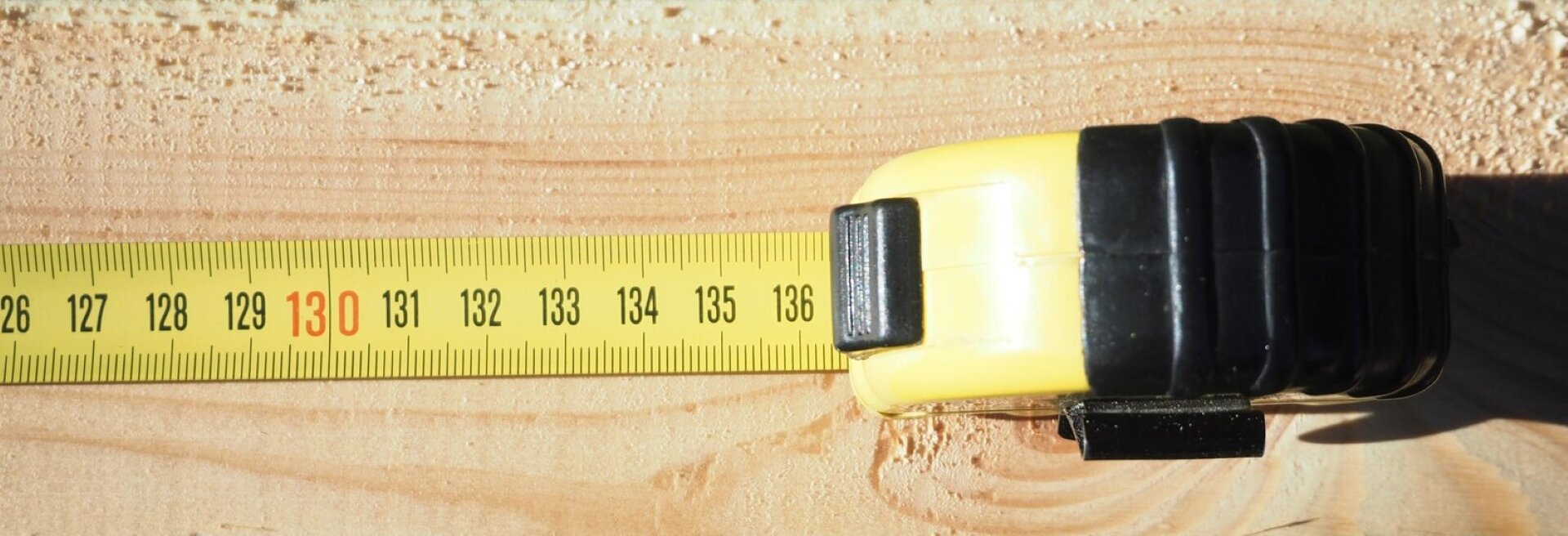 Rys. 2. Zdjęcie poglądowe przedstawia przyłożoną taśmę mierniczą do drewnianej deski.