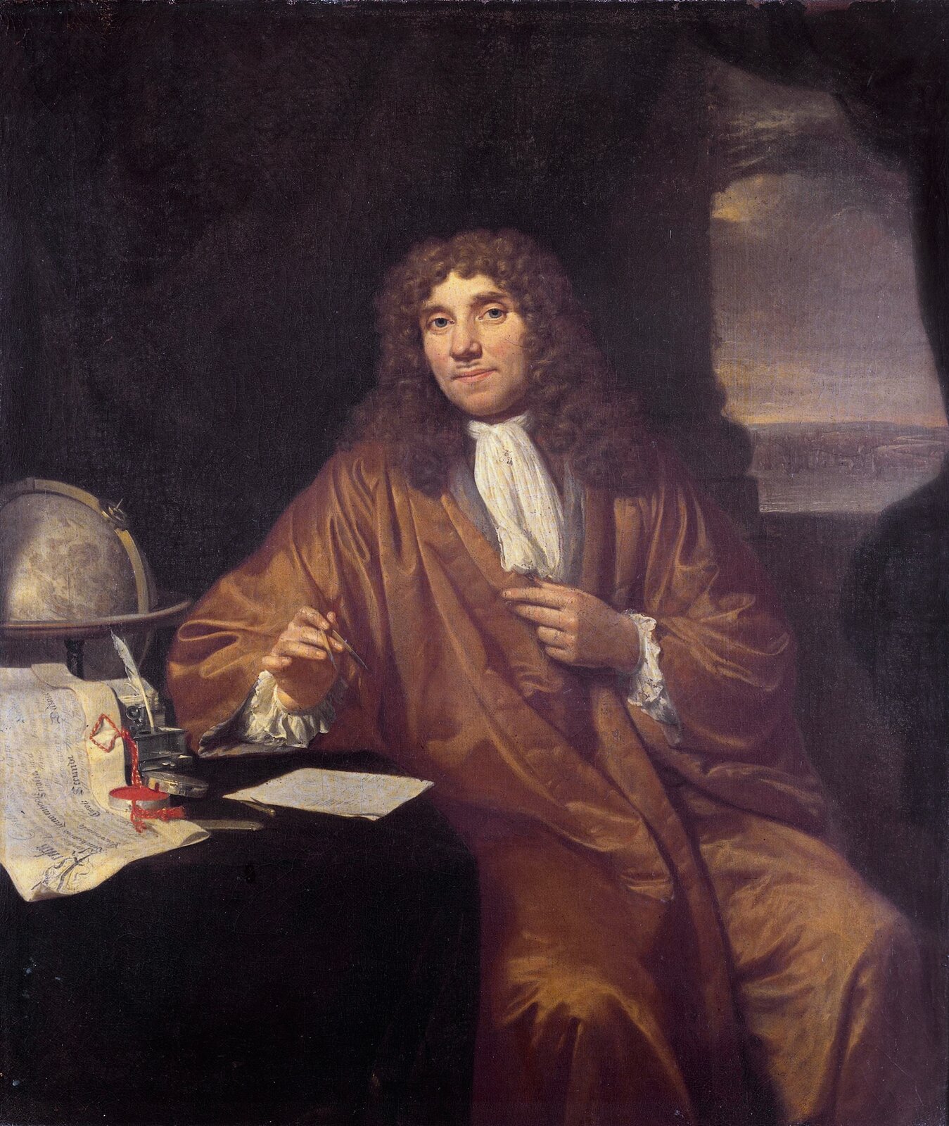 Ilustracja przedstawia portret mężczyzny w stroju historycznym. Strój ten to rodzaj długiego brązowego płaszcza. Mężczyzna siedzi bokiem przy stole, na którym widać na przykład kartki, mapy, globus. Na głowie ma perukę z długimi kręconymi lokami. Jest to Antonie van Leeuwenhoek.