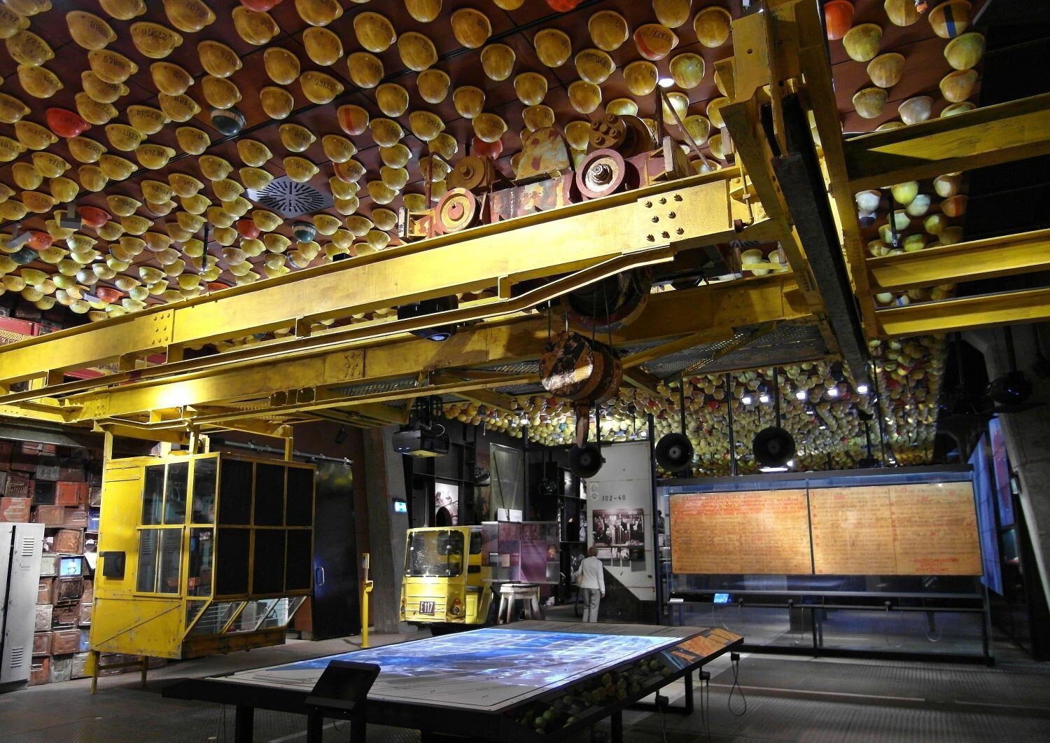 Zdjęcie przedstawiające stałą wystawę w Europejskim Centrum Solidarności. Znajdują się na niej eksponaty ze Stoczni Gdańskiej, m in. kaski robotników, suwnica, tablice z postulatami strajkujących w 1980 roku.