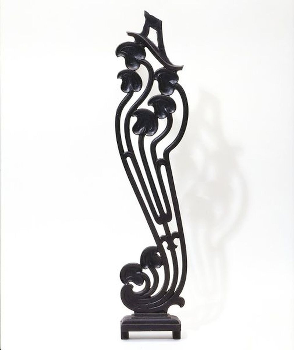Ilustracja przedstawia tralkę balustrady pochodzącą z 1898 roku. Jest to pionowy element balustrady. Podtrzymuje on poręcz. Przedmiot jest w formie profilowanego słupka ze zdobieniami. W tle widzimy jasne, jednolite tło.