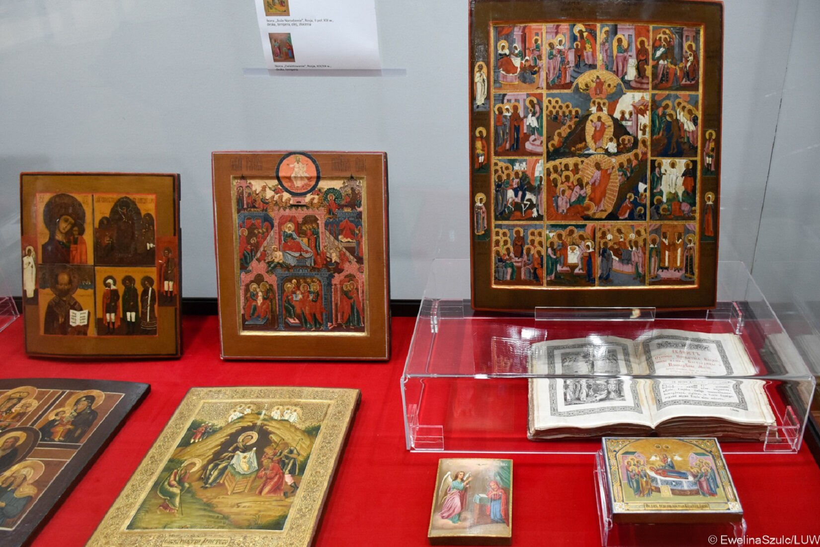 Zdjęcie przedstawia fragment wystawy ikon. Wszystkie osiem ikon umieszczono w szklanej gablocie. Trzy ikony stoją oparte o szybę, a pięć przechowywanych jest w pozycji leżącej – jedna z nich umieszczona została w dodatkowej szklanej gablocie. Każda z ikon przedstawia osobę świętą (przeważnie Maryję z dzieciątkiem) lub opisuje historię Jezusa.  