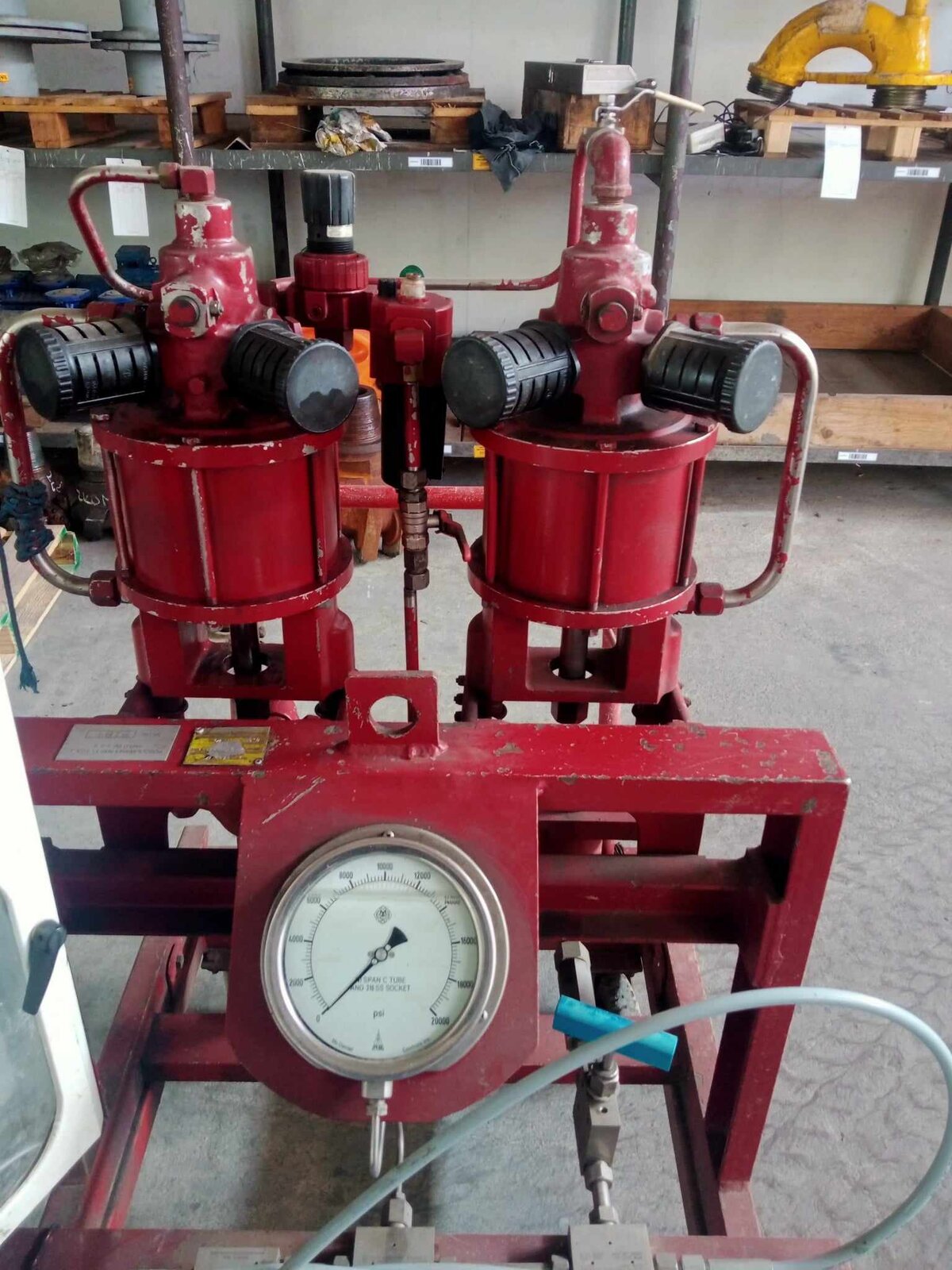 Na zdjęciu widoczny jest agregat wysokociśnieniowy. Agregat wysokociśnieniowy to narzędzie, które zaopatruje w wodę pod wysokim ciśnieniem. Na ekranie widoczna jest tarcza manometru wraz z cienkim przewodem. Za tarczą znajdują się dwa zbiorniki, które połączone są z cienkim przewodem. Z lewej strony widoczny jest fragment rekordografu.