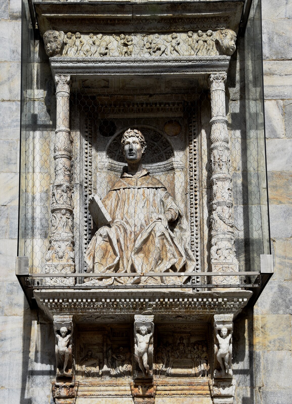 Ilustracja ukazuje rzeźbę Pliniusza Młodszego. Mężczyzna siedzi z lewą ręką na kolanie, a w prawej trzyma tabliczkę. Jest ubrany w długą, zawijającą się szatę. Ma kręcone włosy. Po obu jego stronach znajdują się kolumny ze zdobieniami w kształcie postaci oraz twarzy. Nad kolumnami, w rogach wykuto dziecięce twarze. Belkowanie ozdobiono płaskorzeźbą ukazującą małe postaci dziecięce. Pod główną rzeźbą znajdują się trzy filary ozdobione nagimi ludzkimi postaciami.