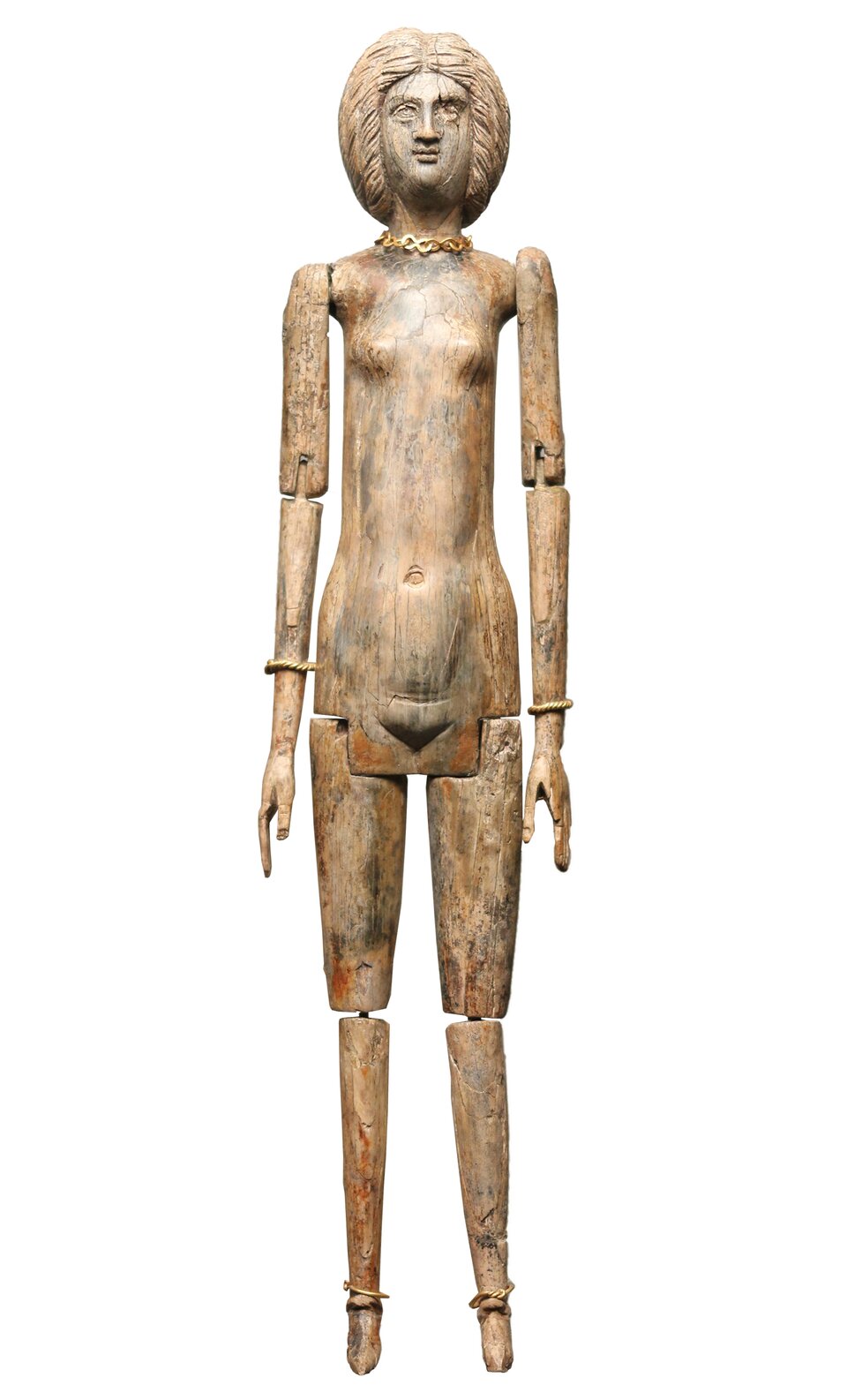 Lalka wykonana z kości słoniowej. Widoczne łączenia na zgięciach ramion, przedramion, bioder i kolan. Figurka smukła, wąska. Zaznaczone rysy anatomiczne twarzy i brzucha, brak narządu płciowego. Na szyi figura posiada złoty naszyjnik, na nadgarstkach bransolety. Dłonie złożone wzdłuż nóg. 