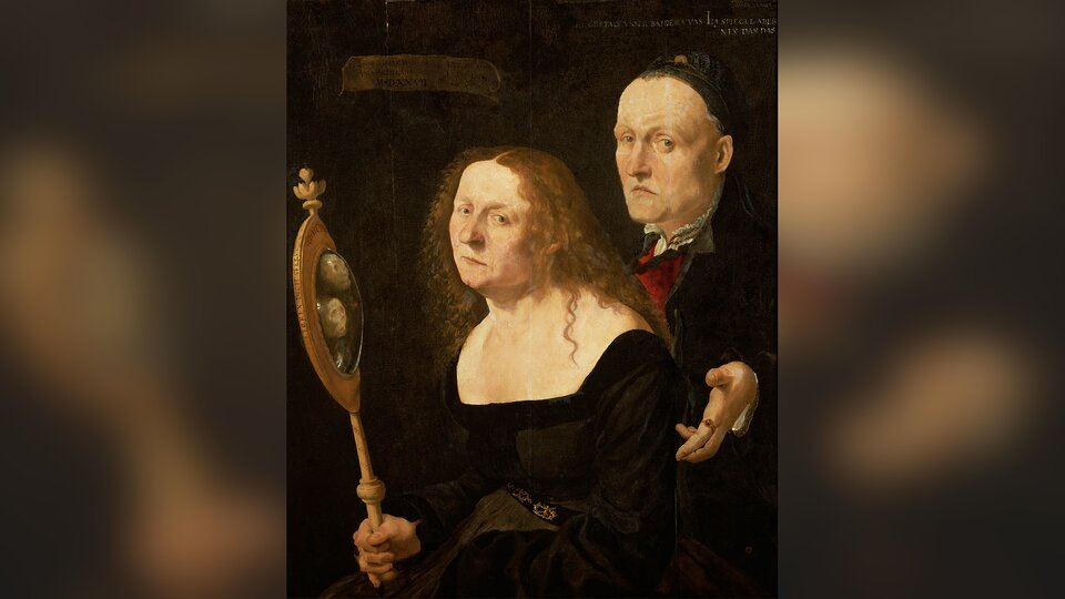 Obraz przedstawia kobietę i stojącego za jej plecami mężczyznę. Kobieta jest starsza, ma zmęczoną twarz. Trzyma w prawej dłoni lustro, w którym zamiast jej odbicia i odbicia mężczyzny widoczne są dwie czaszki. Mężczyzna jest także starszy, ze zmęczoną twarzą.