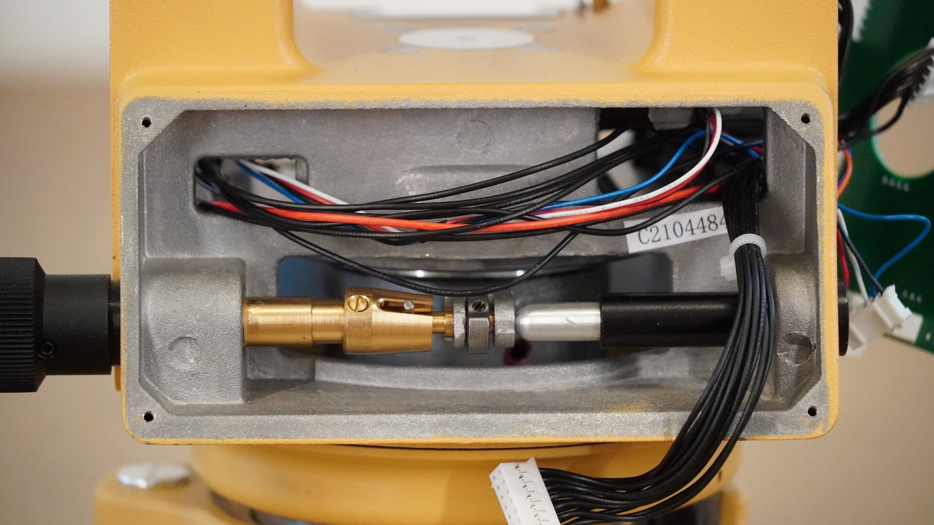 Zdjęcie ukazuje zbliżenie miejsca, w którym był zamontowany wyświetlacz. Po jego demontażu widoczne są cienkie przewody oraz mechanizm sterowany przez śrubę leniwą.