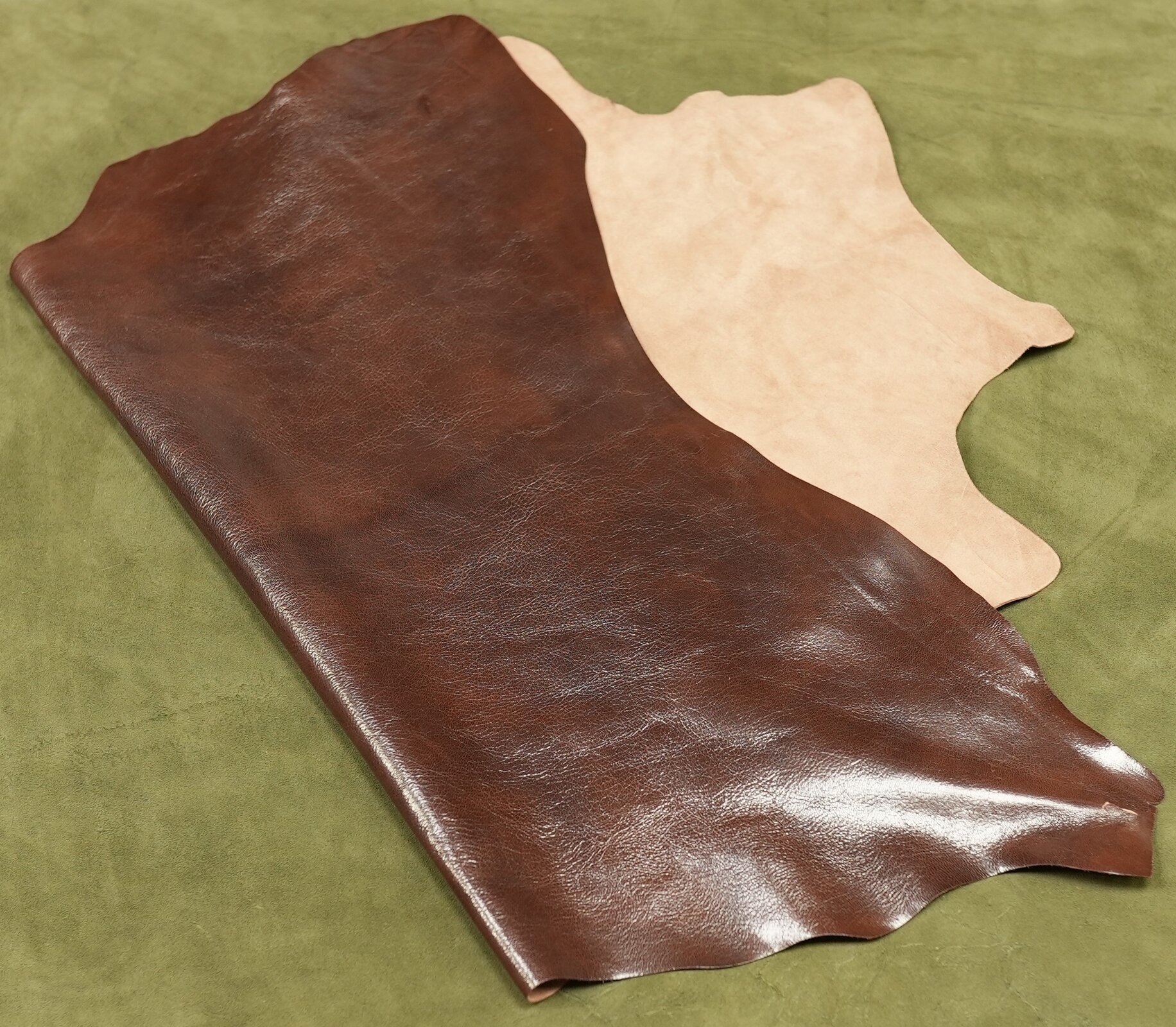 Zdjęcie przedstawia płat skóry koziej. Od strony lica skóra jest ciemnobrązowa, gładka i błyszcząca. Od strony mizdry jest beżowa i chropowata. 
