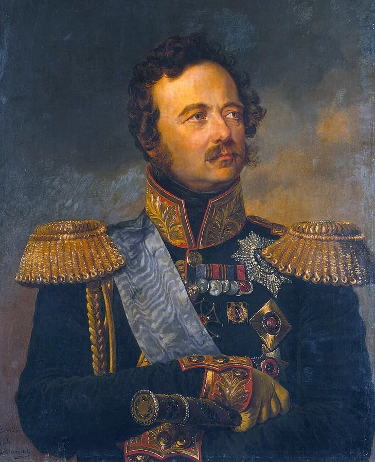Portret mężczyzny w średnim wieku z wąsami, bokobrodami i kręconymi włosami. Mężczyzna ma wysokie czoło, prosty nos, niebieskie oczy, wydatne usta. Ubrany jest w mundur oficerski z wysokim, pionowym kołnierzem typu stójka. Kołnierz jest zdobiony złotym ornamentem, takie samo zdobienie znajduje się na mankietach rękawów. Na ramionach złote naramienniki. Na piersiach liczne odznaczenia. Przez ramię na skos zawieszona niebieska szarfa. W prawej dłoni trzyma rękojeść broni.