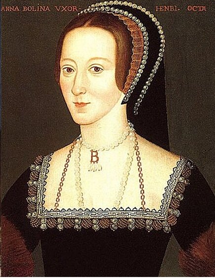 Ilustracja przedstawia portret Anny Boleyn (1501‑1536) - drugiej żony króla Henryka Ósmego Tudora, matki Elżbiety Pierwszej Tudor. Kobieta ma jasną karnację i brązowe włosy. Jest szczupła, ma smukłą szyję. Jej spojrzenie jest bystre, ma duży nos i małe usta. Ubrana w czarną suknię i łańcuch z pereł. Ma czarne nakrycie głowy. 