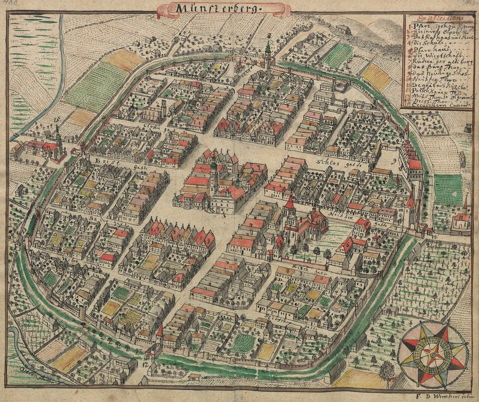 Ilustracja przedstawia widok średniowiecznego miasta. Centrum miasta stanowi rynek wraz z przylegającymi do niego zabudowaniami ratusza miejskiego. Całe miasto podzielone jest ulicami w ten sposób, że zabudowania tworzą prostokątne i kwadratowe skupiska domów. Miasto otoczone jest murem i fosą. Aby dostać się do środka, trzeba przejść przez jedną z czterech bram. Poza murami miasta znajdują się pola uprawne, wieś. Przy jednej z bram stoi kościół. 