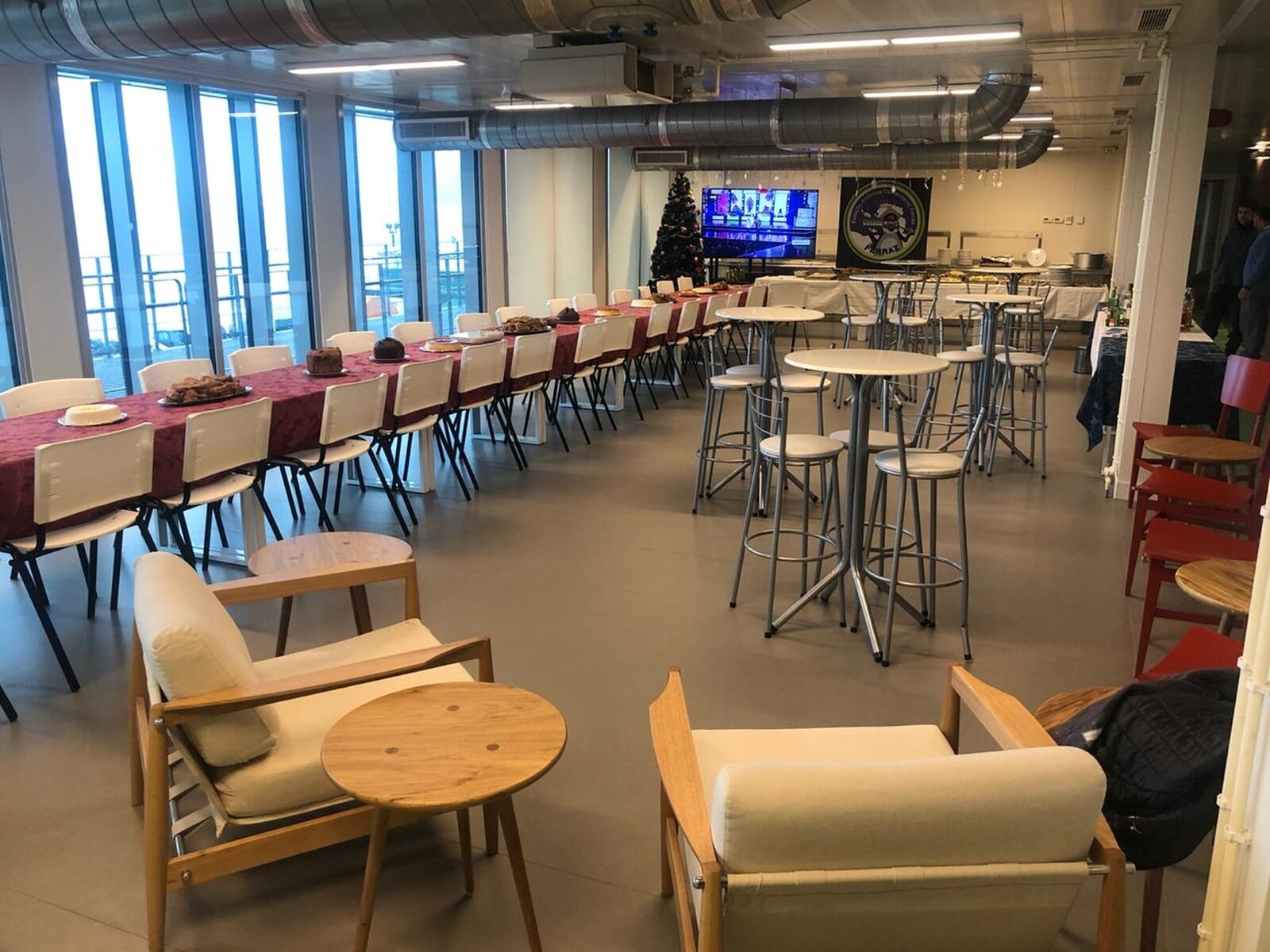 Zdjęcie jadalni, w której wzdłuż ścian rozstawiono nakryte stoły. Po bokach krzesła, na środku pomieszczenie mniejsze, okrągłe stoliki z wysokimi krzesełkami.