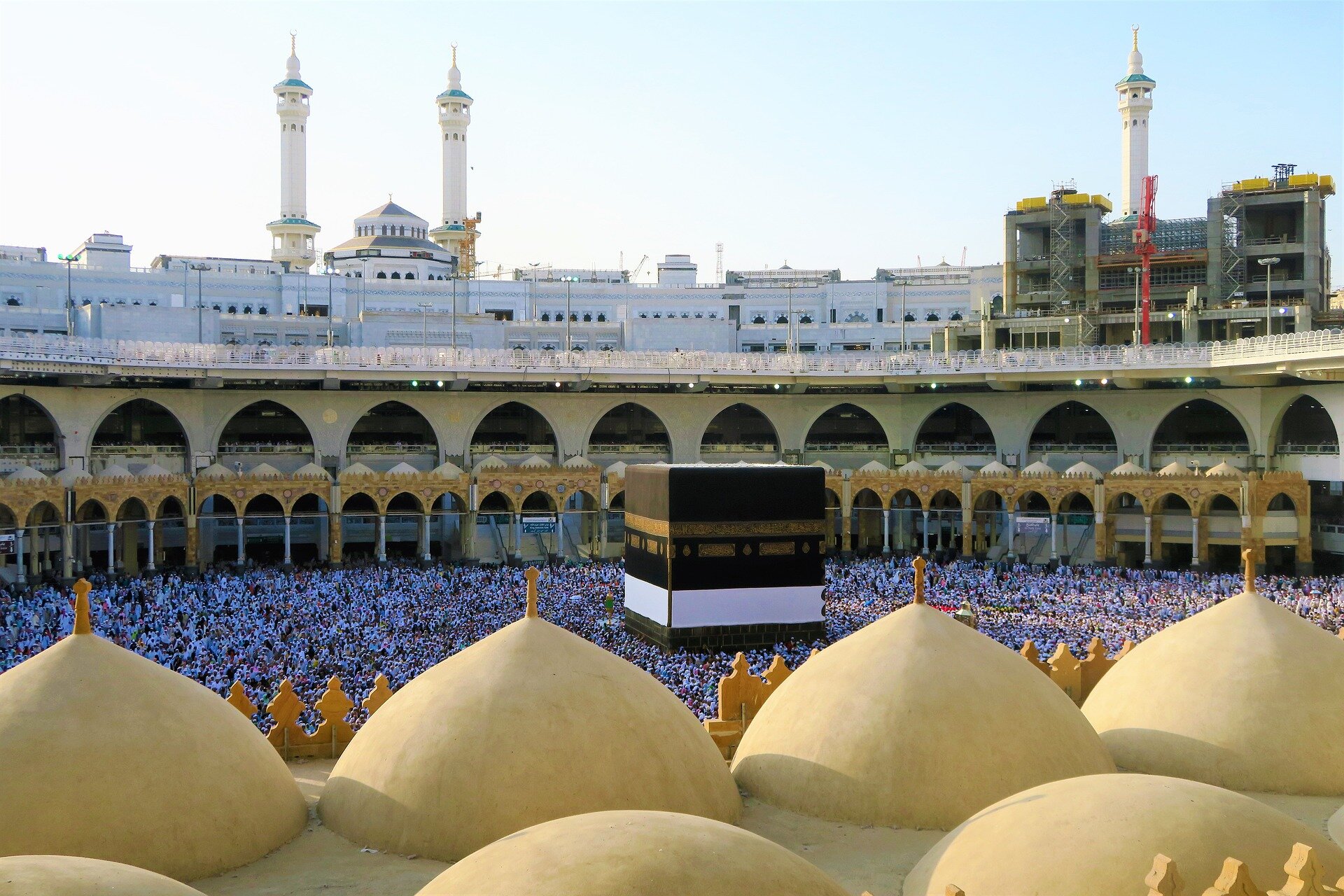 Zdjęcie przedstawia dziedziniec świątyni w Mekce. Jest on okrągły, otoczony kolumnadą i podcieniami. Na dziedzińcu znajdują się setki modlących się ludzi.