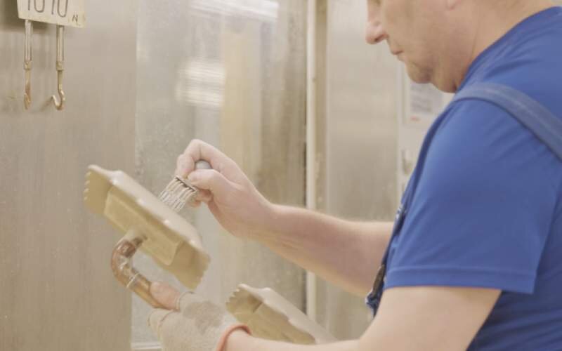 Krok piąty. Sygnowanie wyrobu ceramicznego. Szóste zdjęcie przedstawia mężczyznę oznaczającego wyroby za pomocą specjalnego przyrządu.