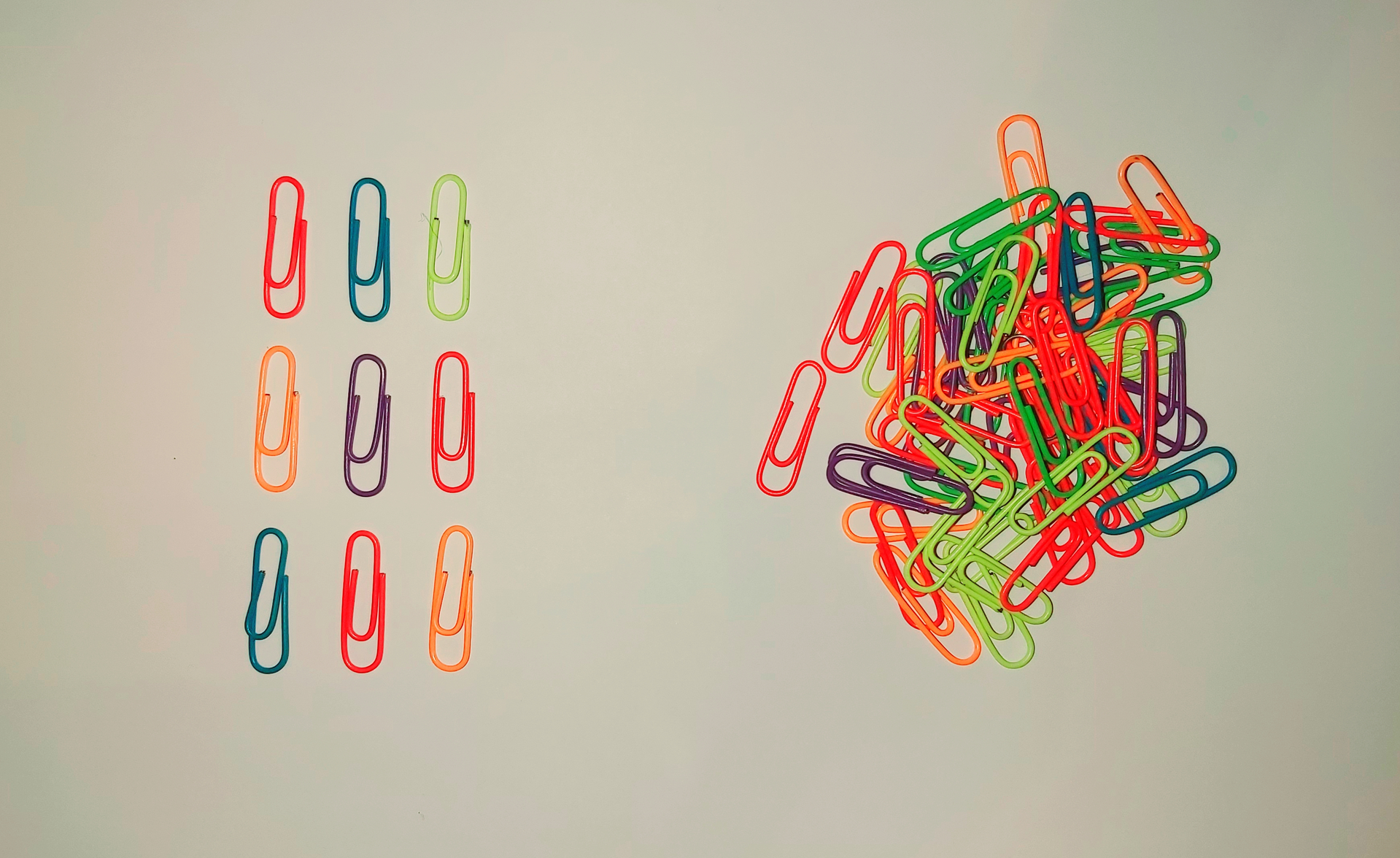Zdjęcie przedstawiające dwa przykładowe układy. Na białym tle po lewej stronie leży dziewięć równo ułożonych w trzy rzędy spinaczy biurowych. Po prawej stronie leży stos bezładnie ułożonych spinaczy. 