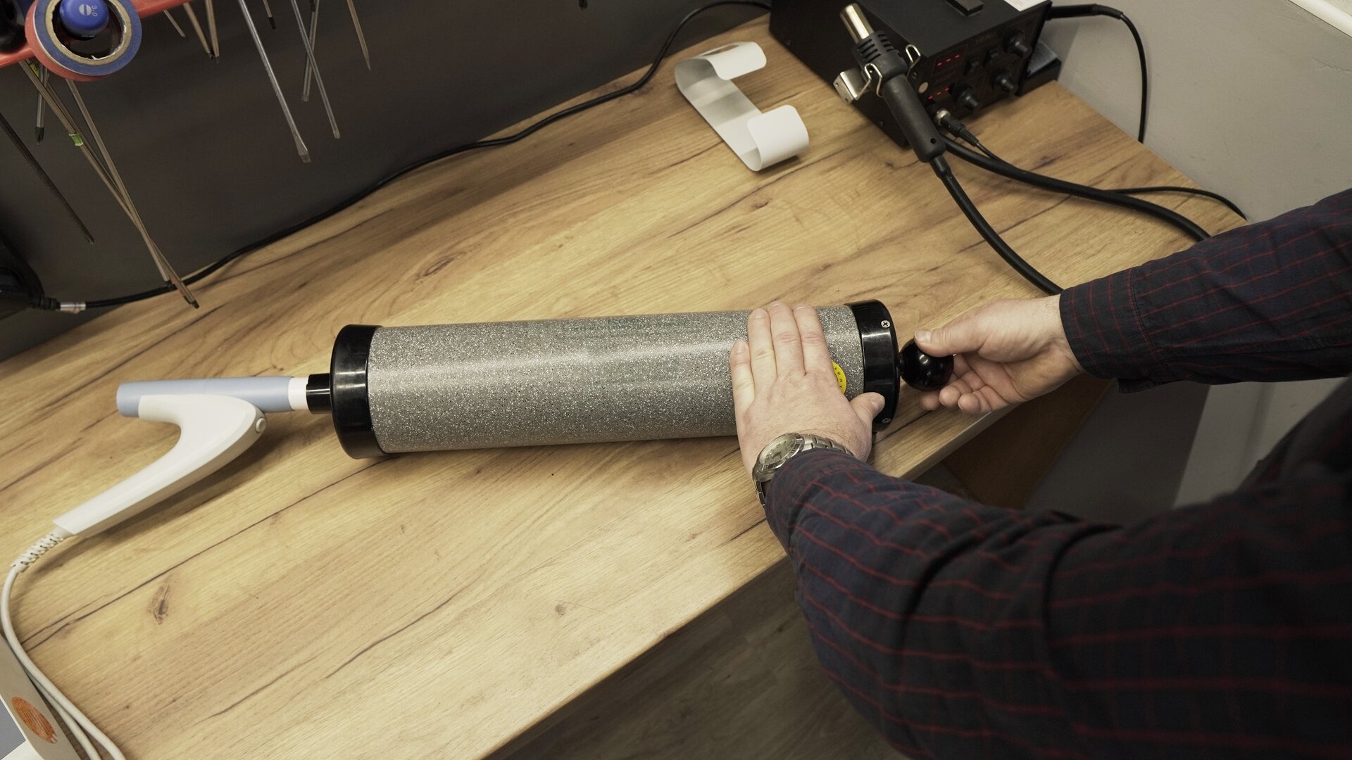 Na zdjęciu technik przygotowuje się do całkowite opróżnienie pompy kalibracyjnej. Lewą ręką przytrzymuje tubę pompy, drugą chwyta rękojeści tłoka.