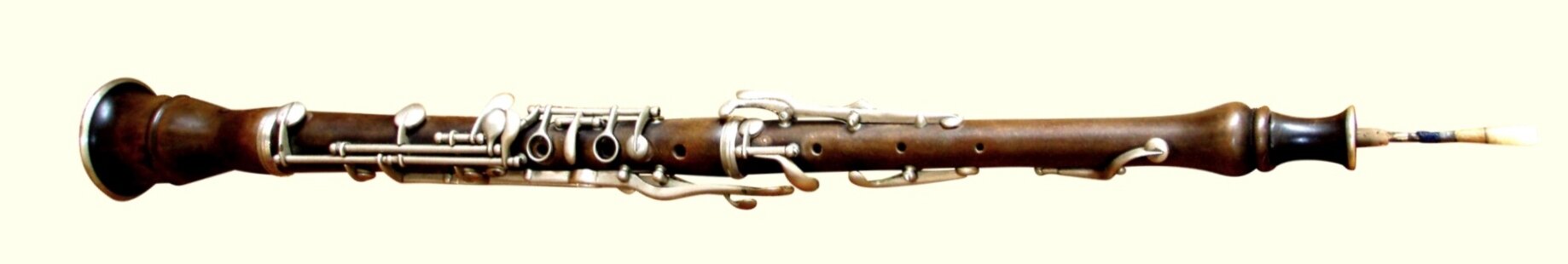 Zdjęcie przedstawia obój wiedeński. Instrument jest drewniany, prosty, z okrągłymi otworami. Na nim znajdują się skomplikowane metalowe elementy. Niektóre z nich to klapki, są też dłuższe elementy pomiędzy otworami. Tylny koniec jest nieco rozszerzony, a ustnik to cienka rurka.