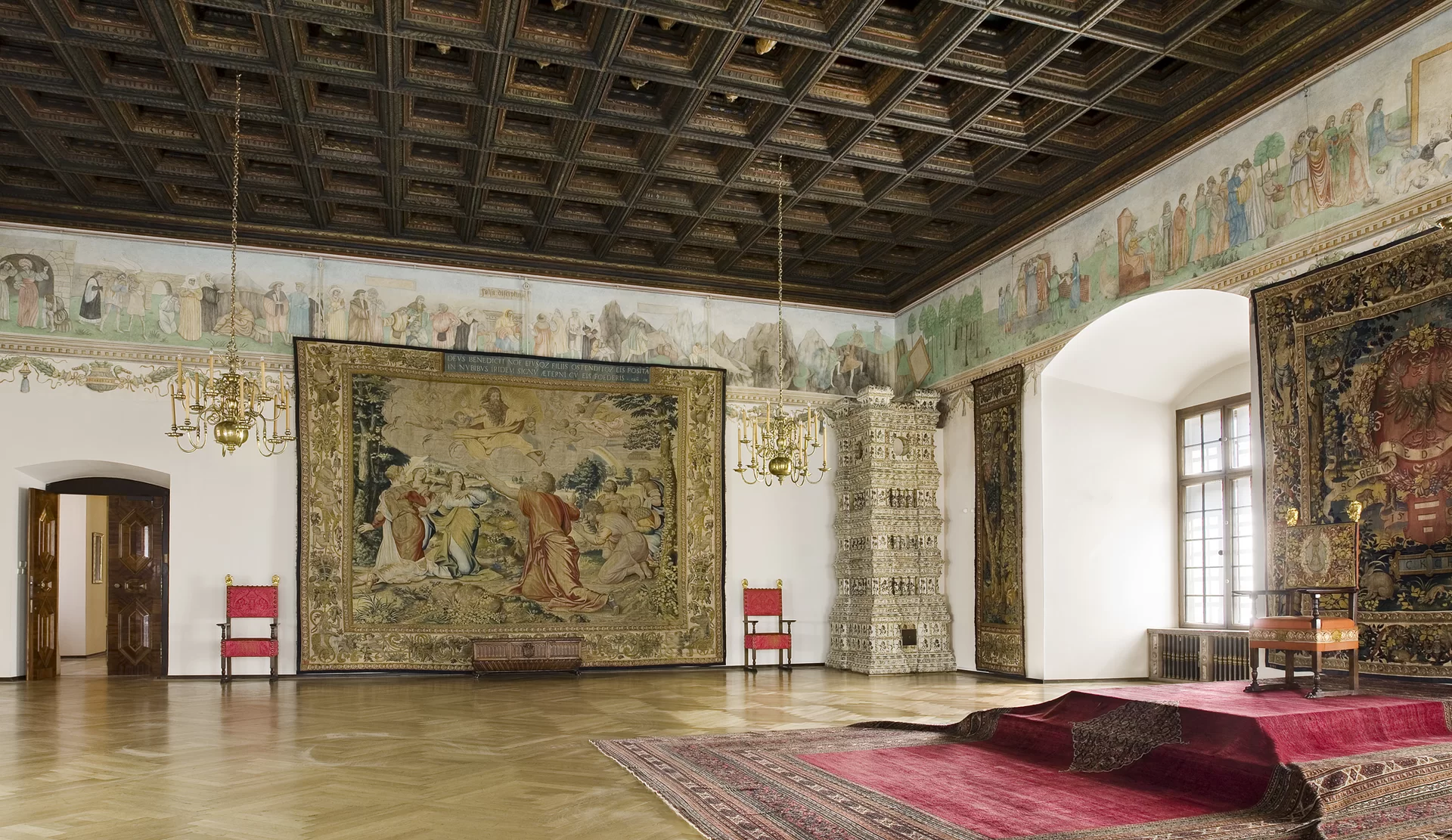 Fotografia przedstawia: Wawel - salę Poselską. Ściany zdobi fresk pędzla Hansa Dürera (1532) z alegorią historii życia ludzkiego, ukazujący poszczególne etapy życia człowieka. Sala ma jasna posadzkę zasłoniętaczęściowo dywanem. Ściany sa kolorowe, ozdobione malowidłami. Sufit jest ciemny.