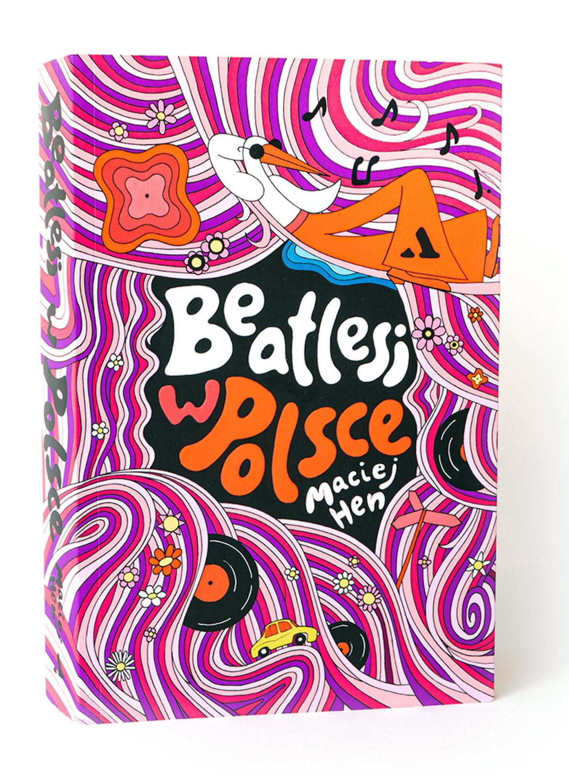Ilustracja przedstawia zdjęcie książki autorstwa Macieja Hen pod tytułem „Beatlesi w Polsce” [czytaj: bitlesi w polsce]. Tytuł i autor są w barwach polskiej flagi i stanowią centralny punkt okładki. Ramka wokół jest nasycona kolorami takimi jak: różowy, fioletowy, biały, pomarańczowy, czarny oraz żółty. Nad tytułem książki namalowany jest bocian leżący na hamaku, ubrany w białą koszulę i pomarańczowe spodnie oraz okulary przeciwsłoneczne w stylu hipisowskim. W dolnej części znajdują się płyty winylowe, żółty pojazd oraz kolorowe kwiatki, które znajdujące się także w pozostałej części okładki.  