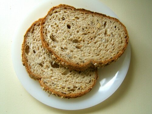 Kolorowa fotografia przedstawia dwie owalne kromki chleba ułożone na białym talerzyku.